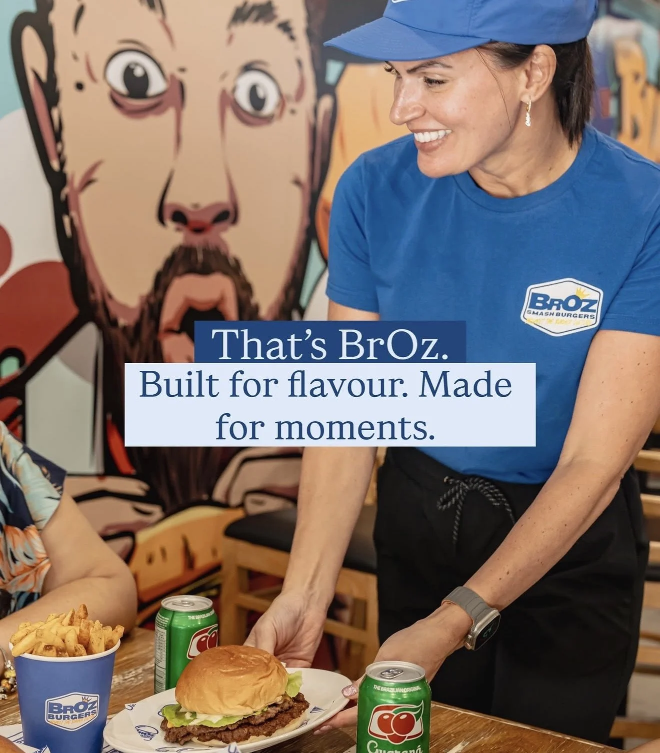 BrOz Burgers Sydney staff serving a fresh smash burger with fries, wearing branded uniform inside the restaurant.