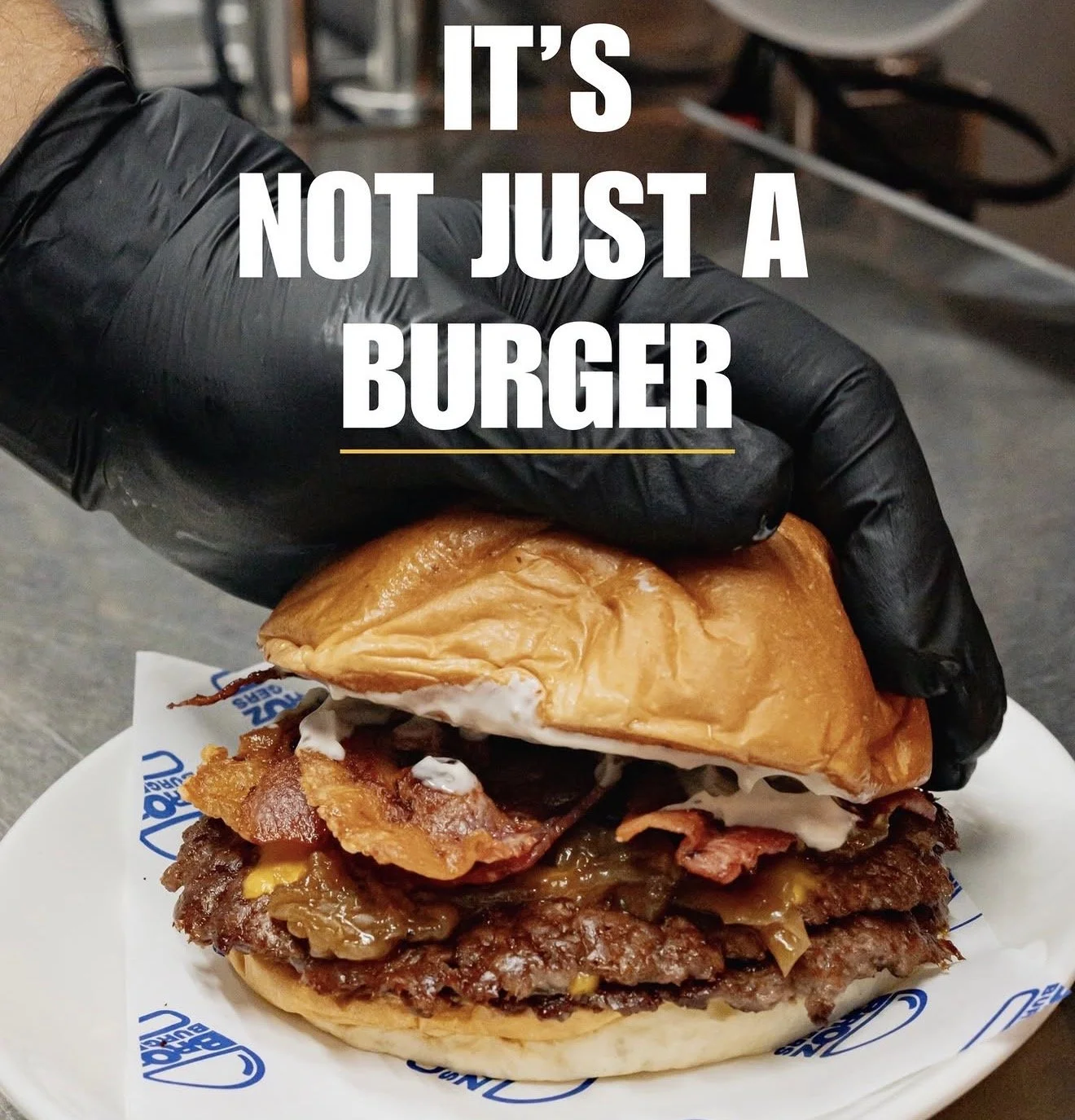 Double smash burger with bacon from BrOz Burgers Sydney, held by chef, with melted cheese and house sauce.