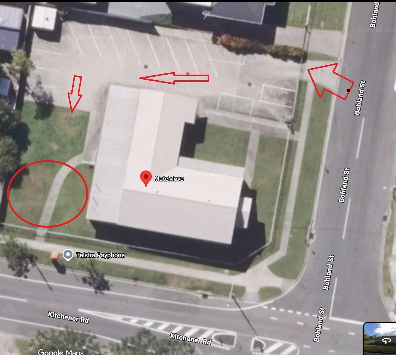 Aerial view of a building with a lawn and parking lot, located at the corner of Bohland Street and Kitchener Road, with red arrows pointing to pathways and a red circle highlighting the lawn area.