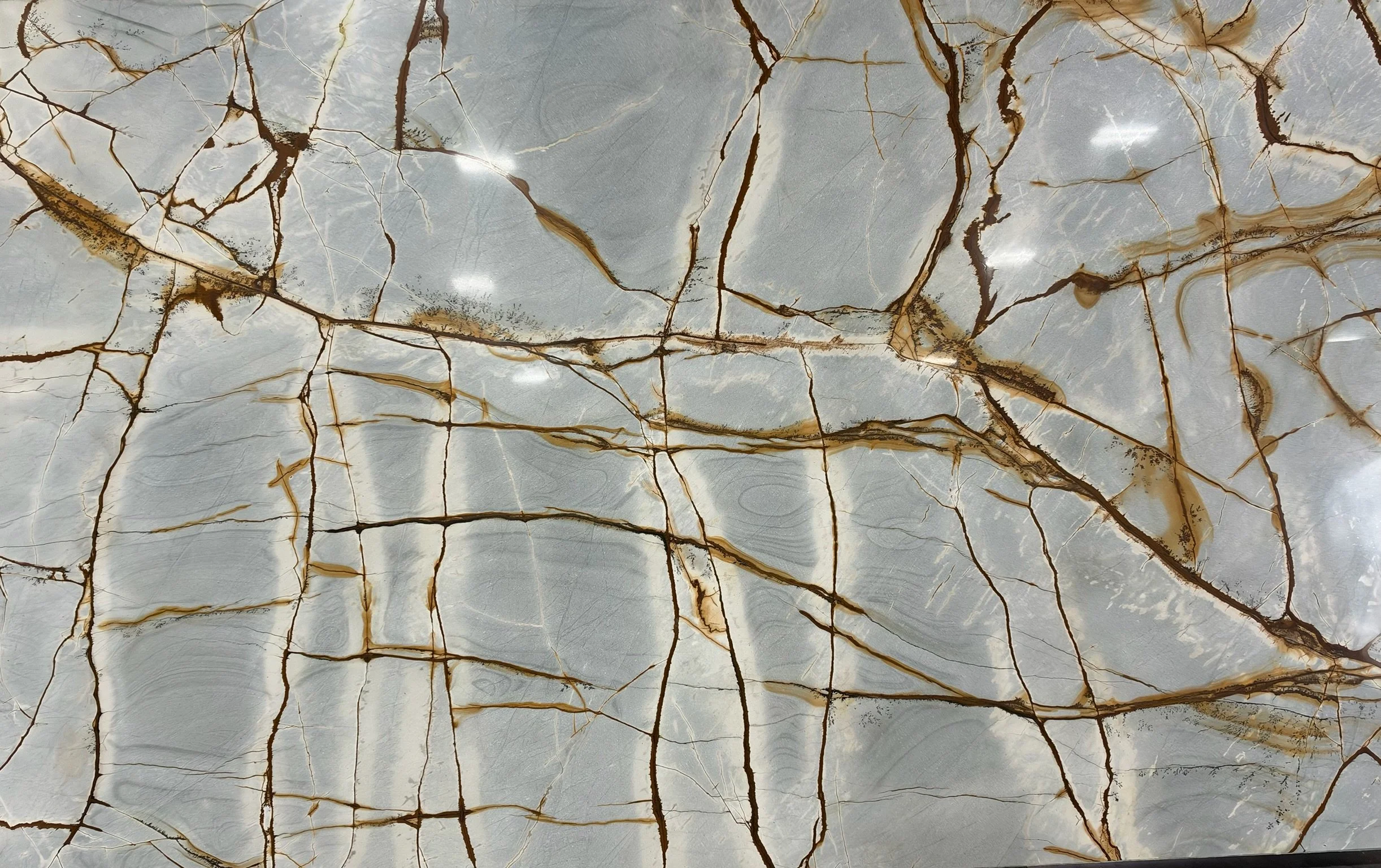 Silver-gray stone slab with dramatic gold and bronze veining at Marbella Stone