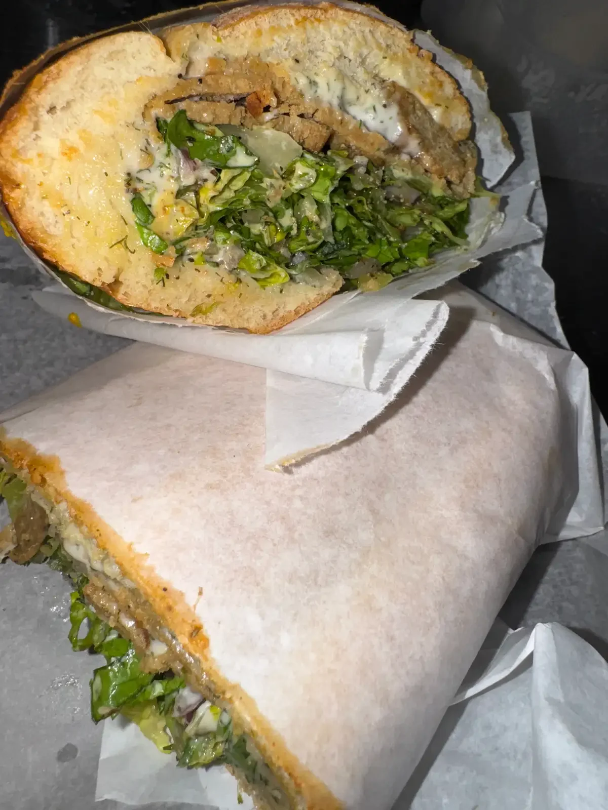 Da Grinder plant-based deli sandwich at RHW, cut open to show its filling and greens