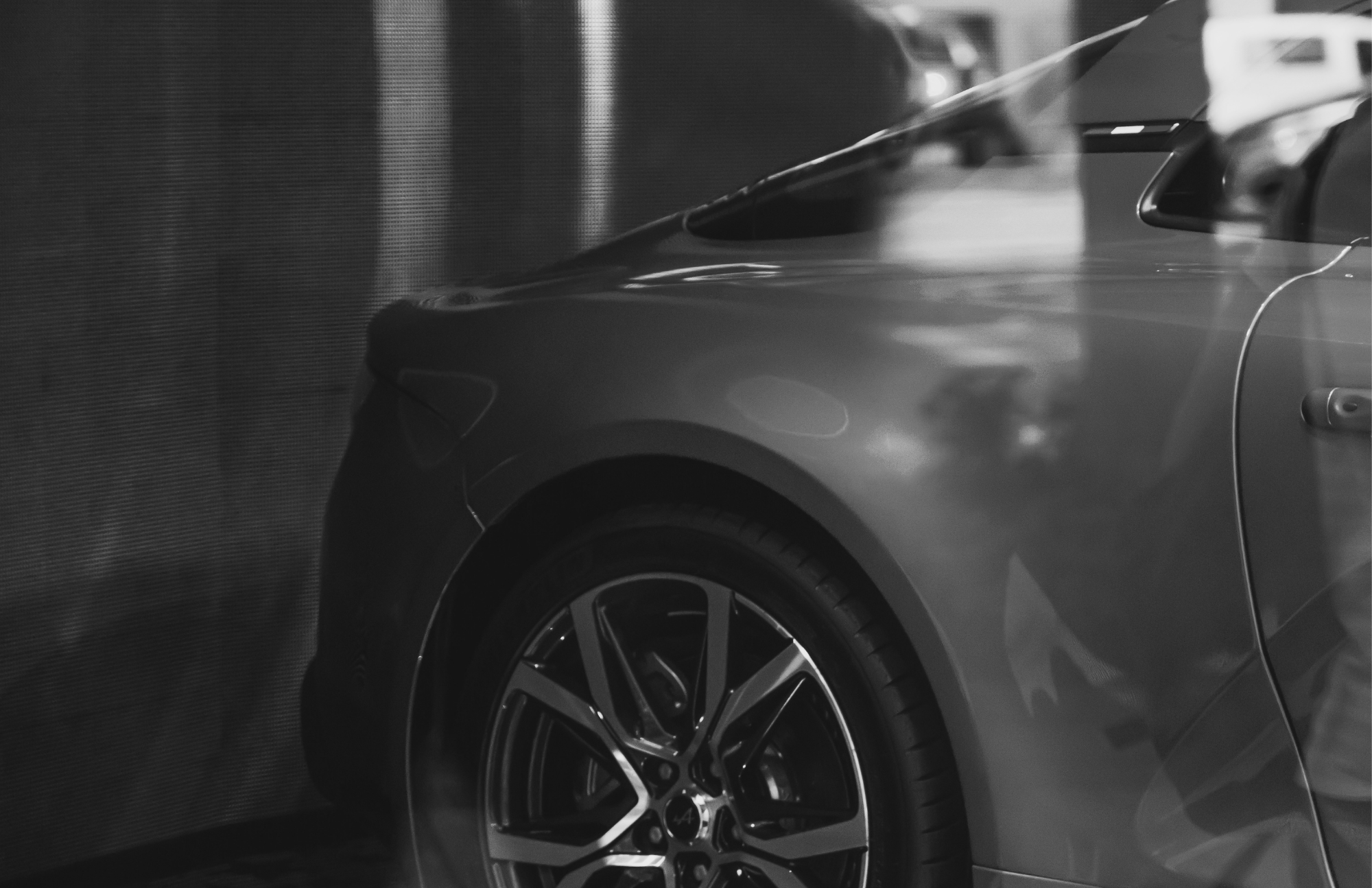 Close-up of a modern car's front end, showing the wheel, fender, and side mirror.
