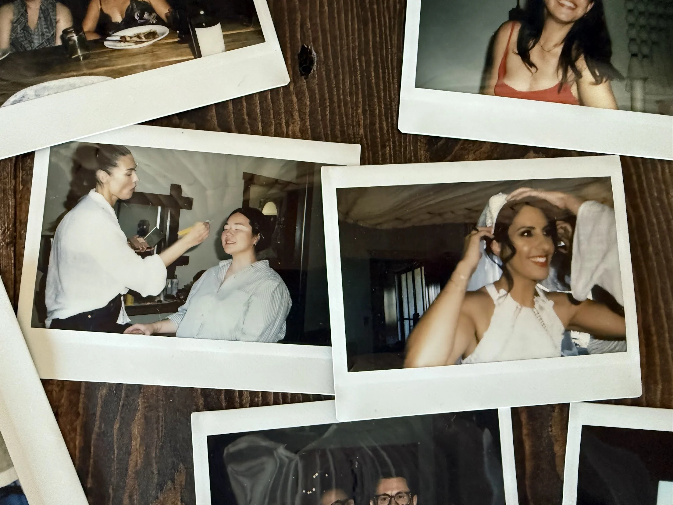 Polaroid photos of women getting ready for a wedding, one is having makeup applied while another is putting on a veil, on a wooden table.