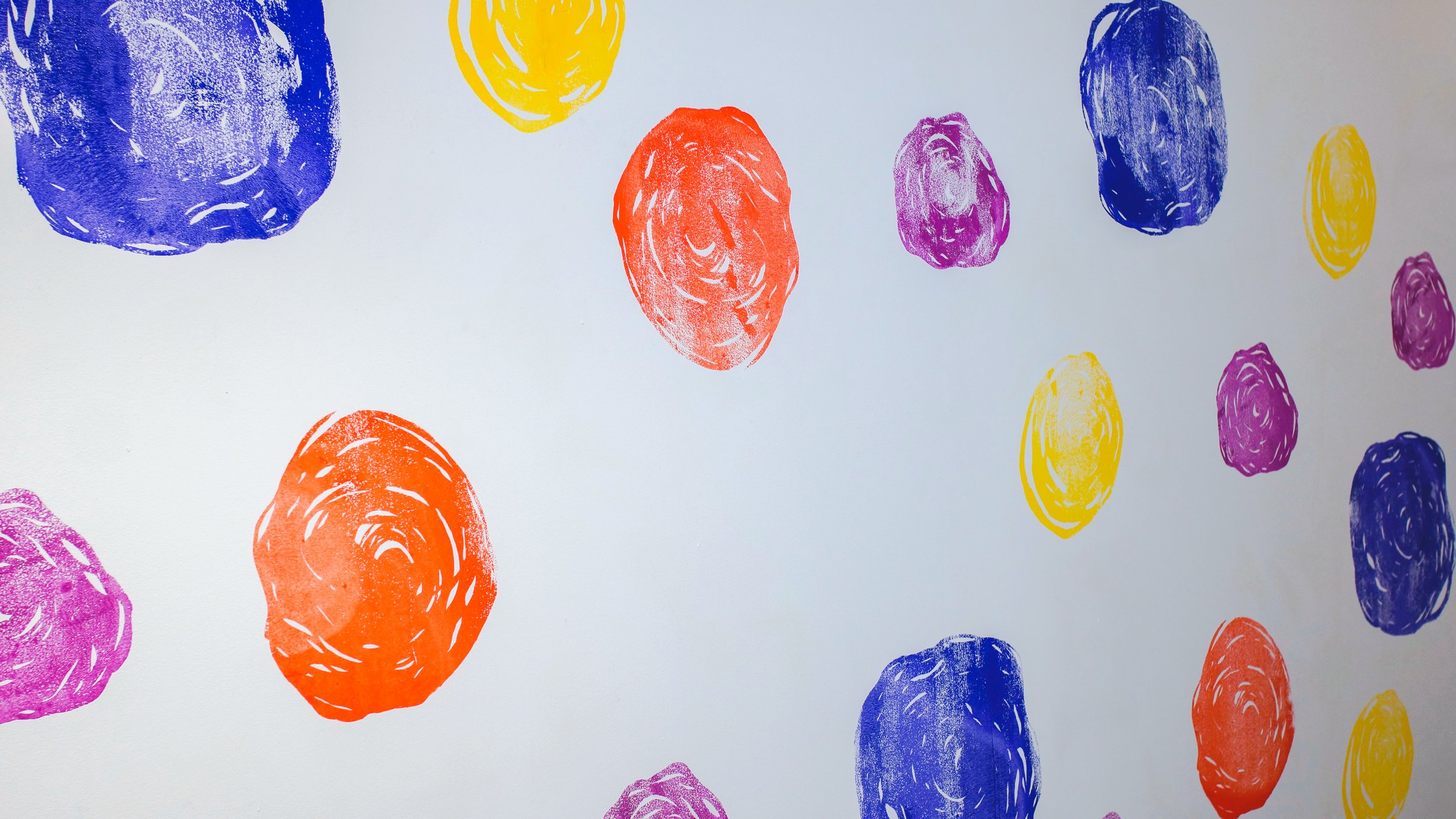 Colorful abstract dots in purple, yellow, orange, pink, and blue scribbled on a white background.