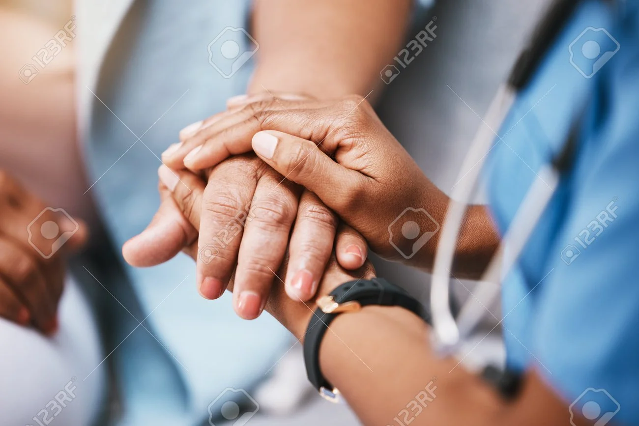 A healthcare professional holding and comforting an elderly patient's hand.