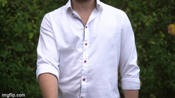 Person wearing a white button-down shirt with rolled-up sleeves, outdoors with green foliage in the background.