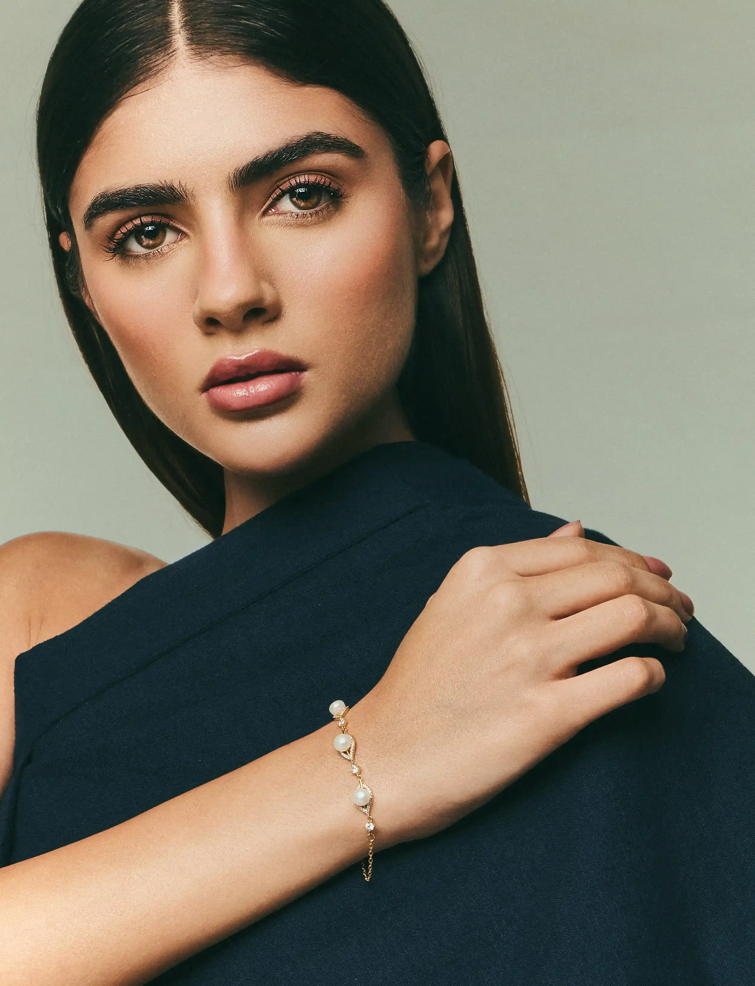 Close-up of a young woman with dark hair, wearing a dark-colored top and a pearl bracelet, looking directly at the camera. Kushal's Fashion Jewellery, Anandclix, Bangalore, advertising photographer, Fashion photographer.