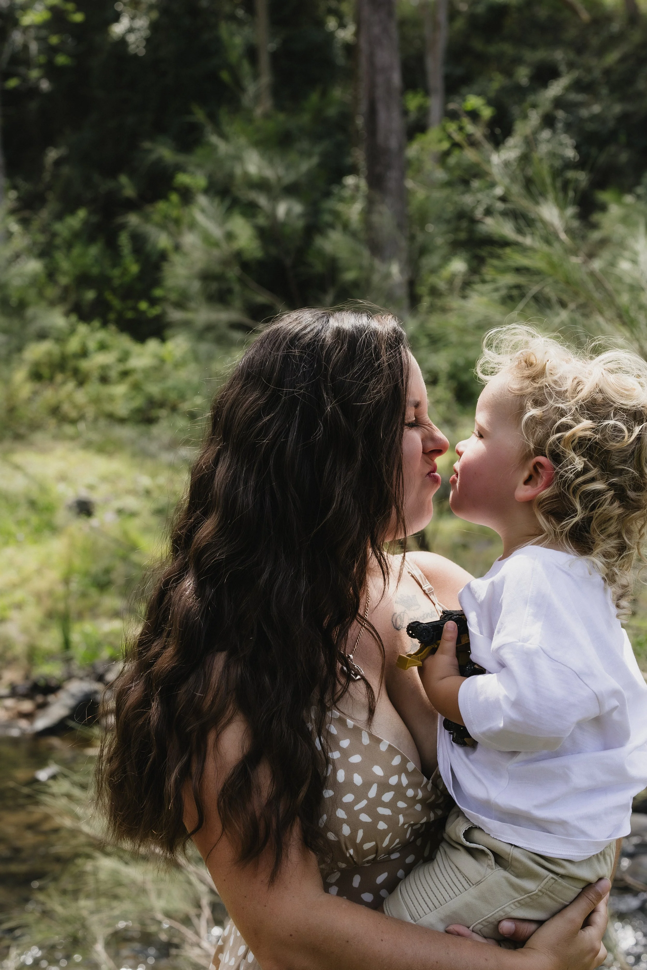 mother holding child outdoors during golden hour family photography session - scenic rim 
