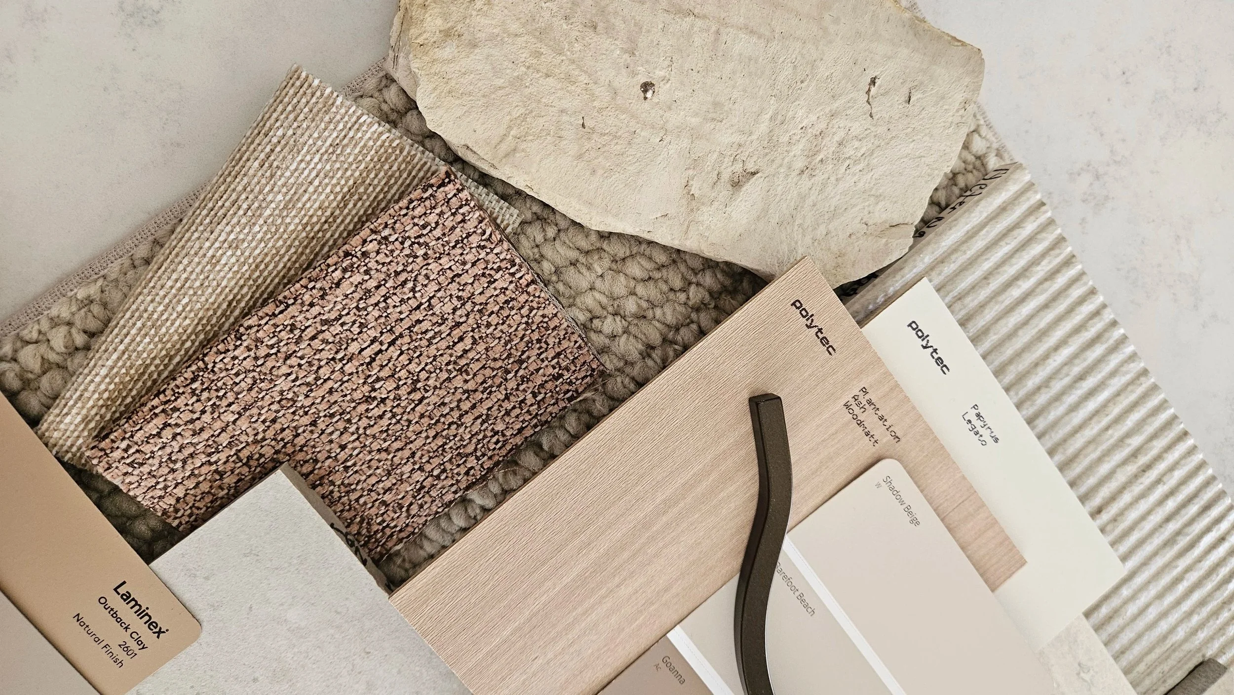 Material Board. Sample swatches of flooring and tile materials, including a beige textured rug, a pink and beige woven carpet, a textured beige tile, and patterned tile samples.