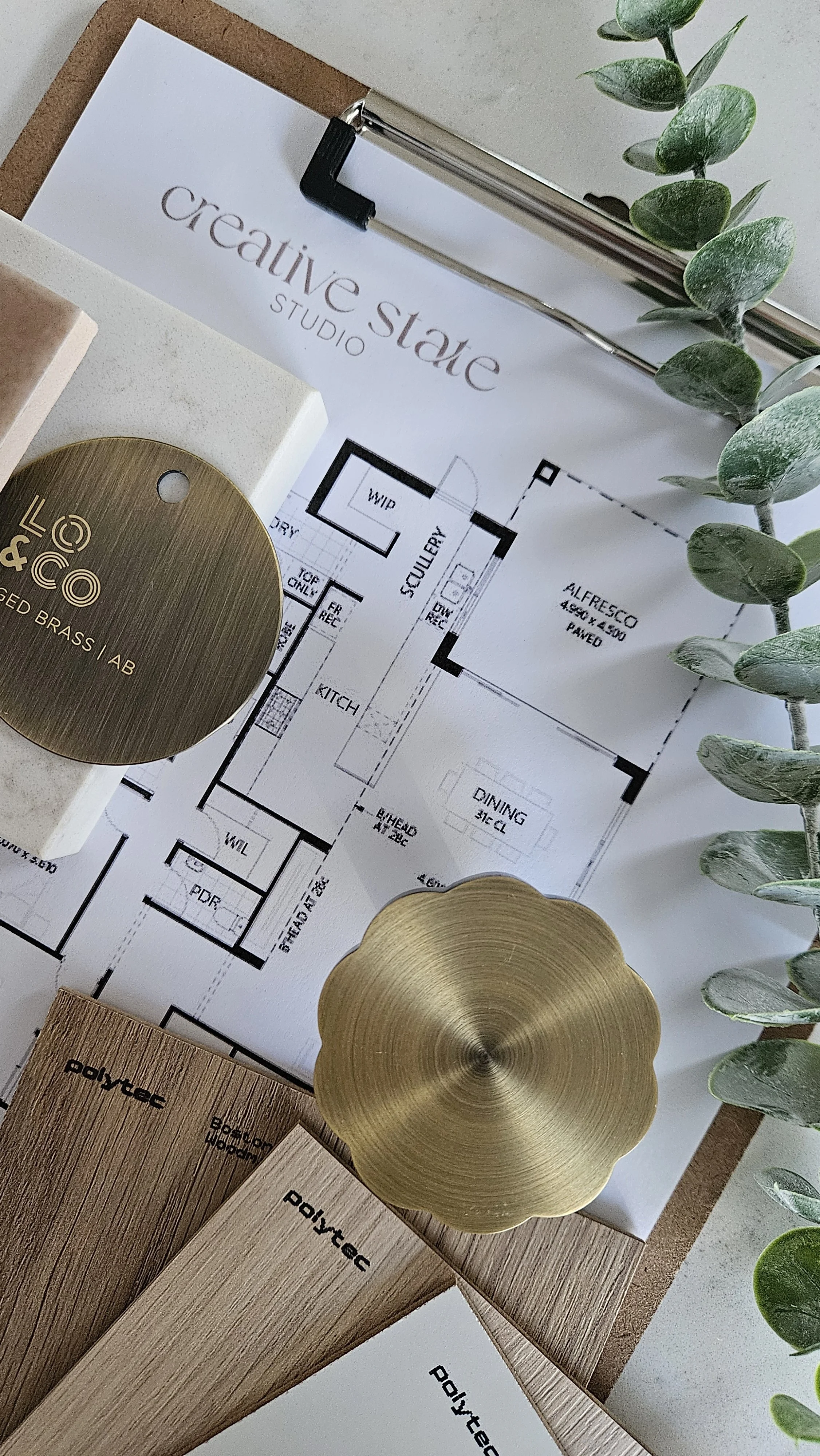 Interior designer workspace with floor plans, material samples and brass finishes