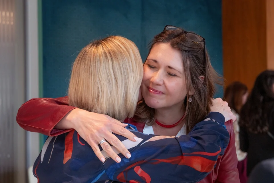 Tatiana Poliakova sharing an embrace at a women's leadership event.