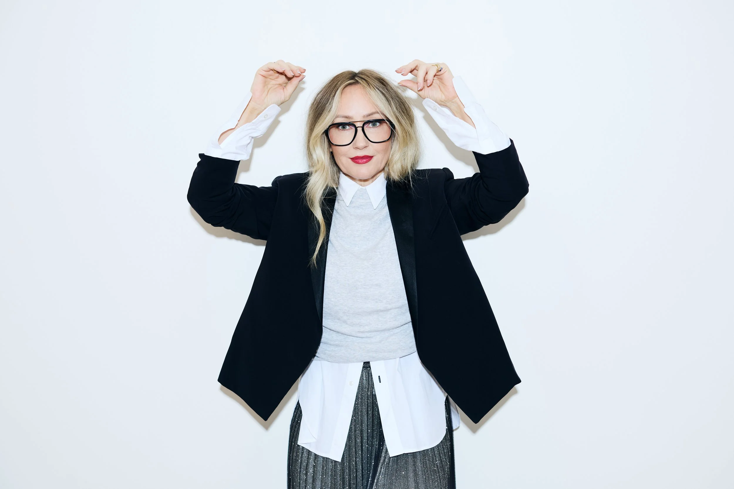 Danielle Butcher wearing red lipstick with arms raised, posing playfully for the Red for a Reason social media campaign