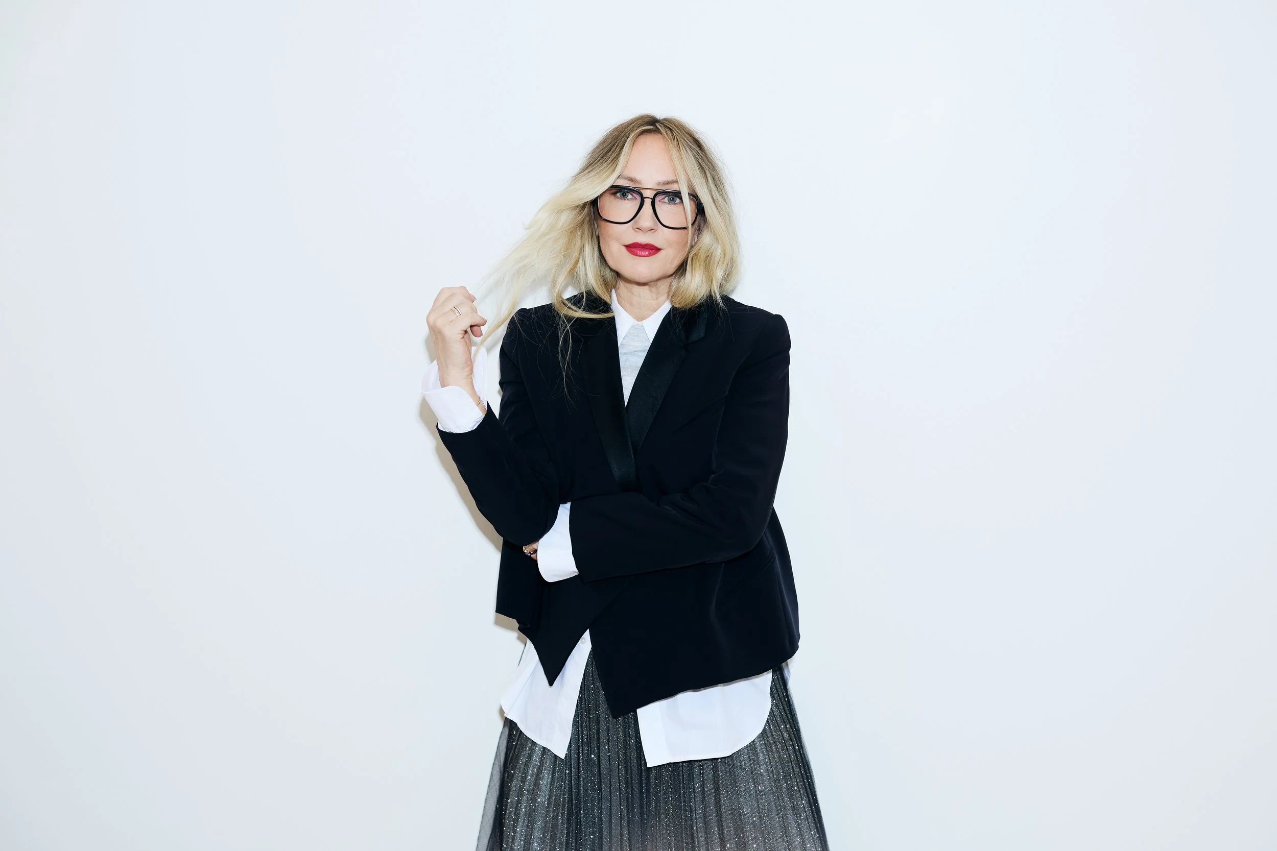 Danielle Butcher wearing red lipstick and a black blazer, arms crossed, for the Red for a Reason campaign