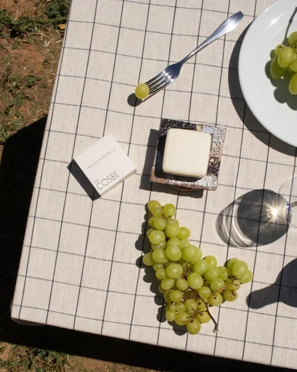 Champô sólido numa mesa ao ar livre com uvas verdes ao redor