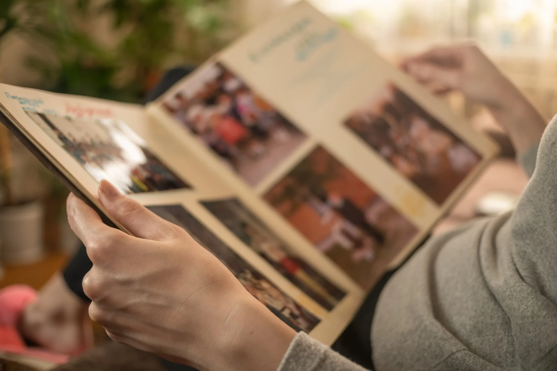 Person holding a photo album and looking at photos inside.