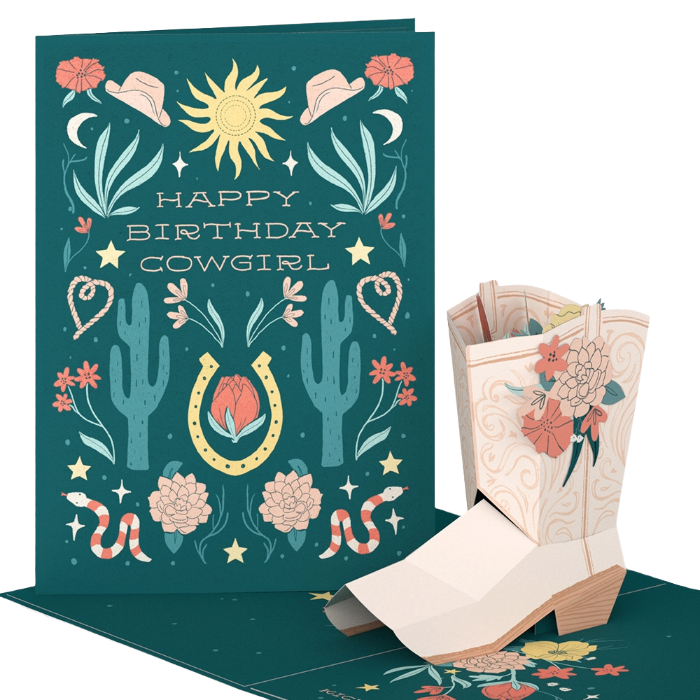 A birthday card with a Western cowgirl theme featuring cacti, roses, snakes, and cowboy hats, with the message 'Happy Birthday Cowgirl.' The card is accompanied by a matching paper pop-up and decorative envelope.