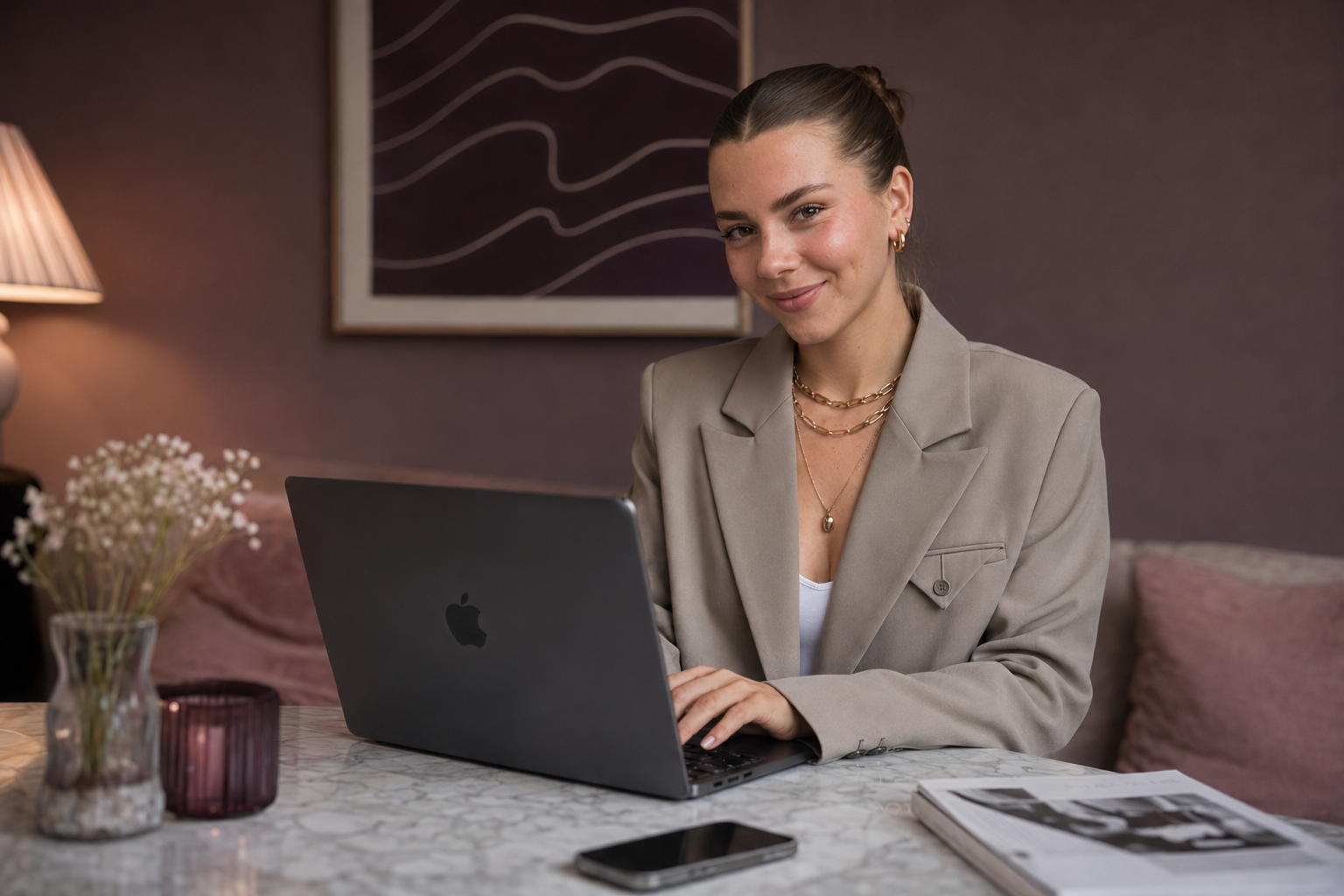 Junge Frau arbeitet an einem Laptop in einem Wohnzimmer, umgeben von Büchern und Dekorationsgegenständen.