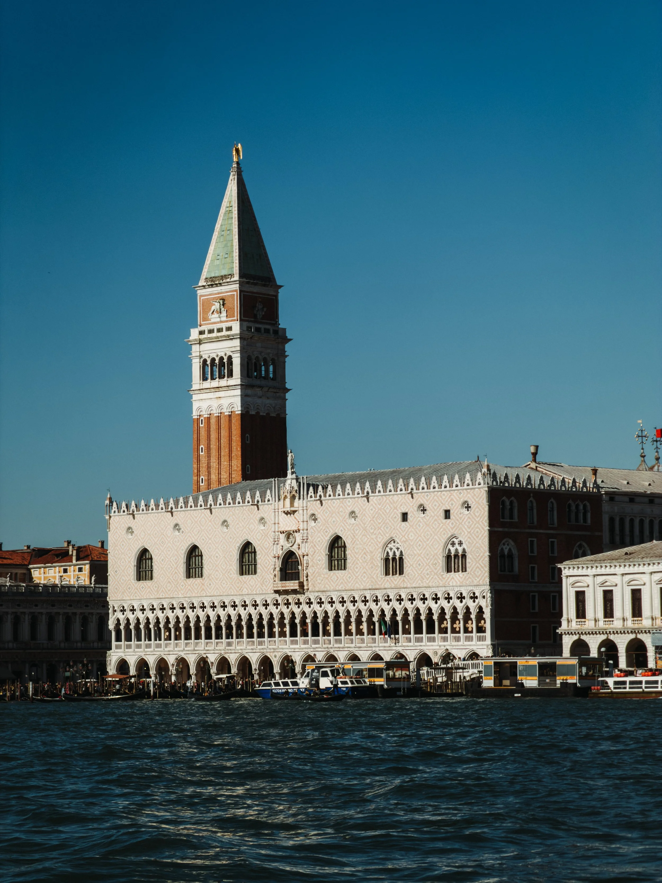 A view of the historic St. Mark's Campanile tower and the Doge's Palace in Venice, Italy, seen from the water.