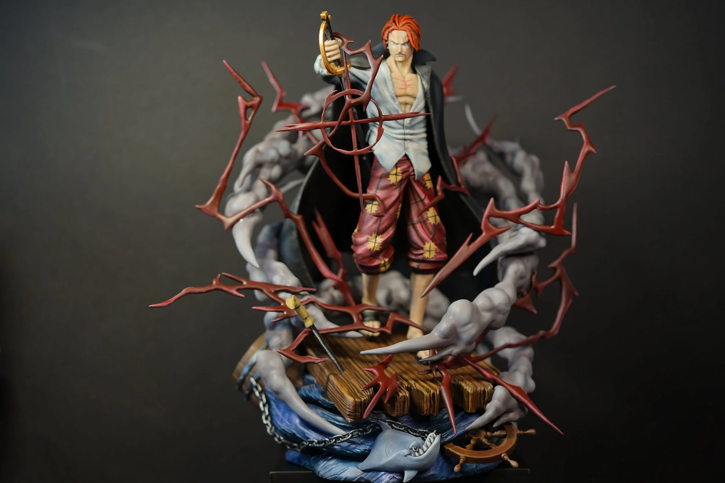 Figure of Shanks from one piece, with red hair, standing on a wooden platform surrounded by water, lightning, and clouds, holding a sword.