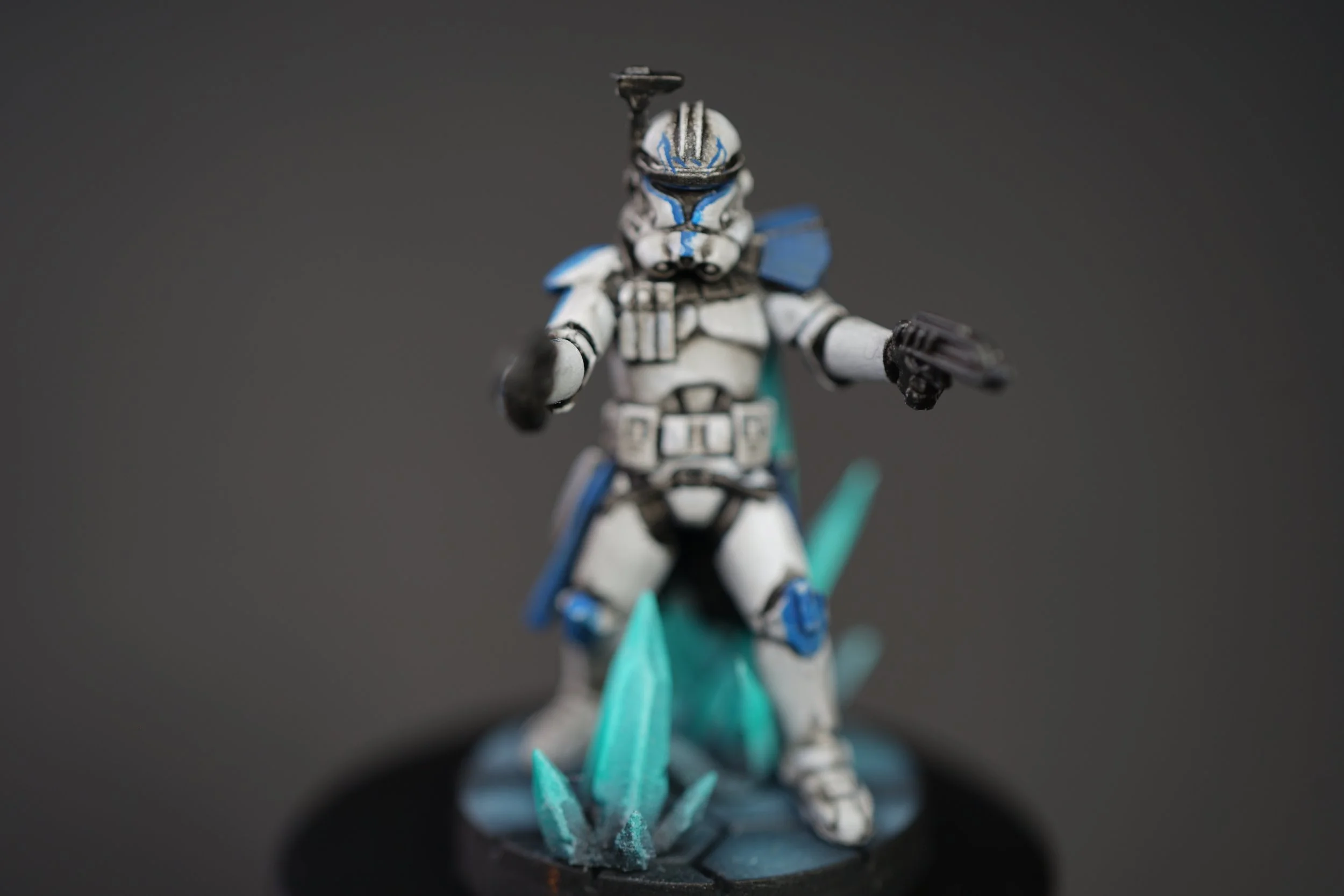 A miniature figurine of clone captain Rex from Star Wars, holding two blasters, standing among crystal spikes, against a dark background.