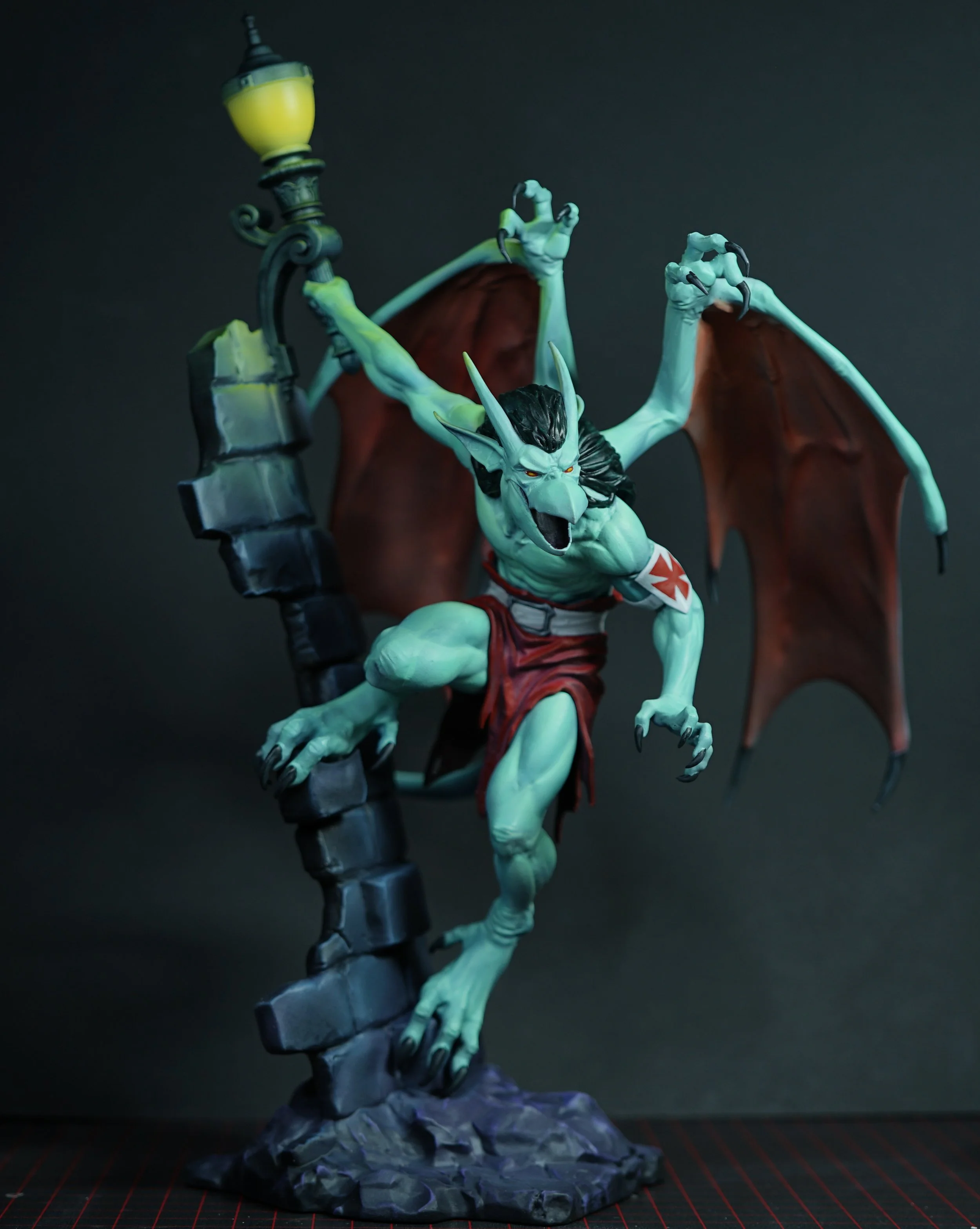 A detailed model of a fantasy creature with wings, horns, and sharp claws, perched on a stone base beside a streetlamp, with a dark background.