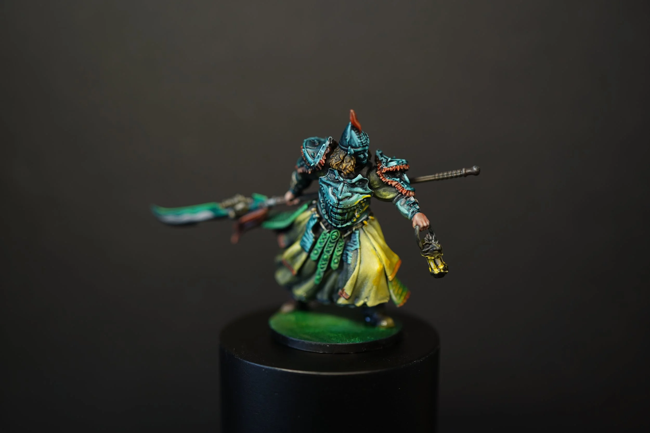 Colorfully painted miniature figure of a warrior from Kingdom Death in armor, holding a spear and glowing lantern, standing on a green base against a dark background.