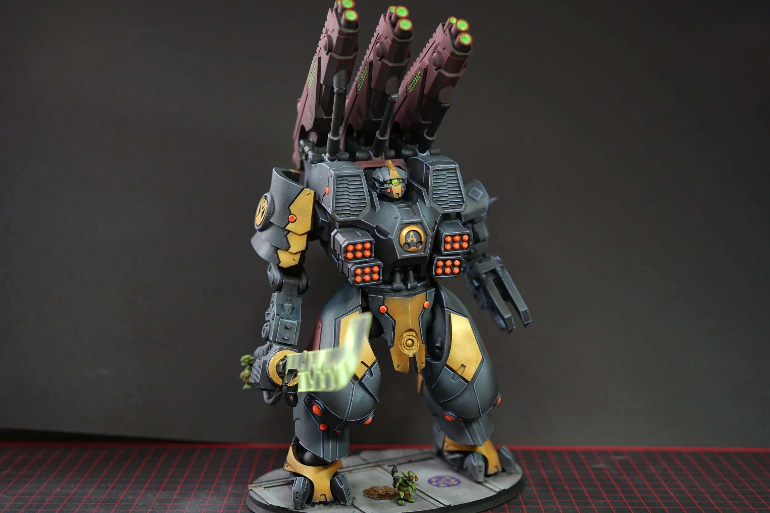 A detailed model of a futuristic robot or mech with large guns on its back and a small goblin at its feet, set against a plain dark background.