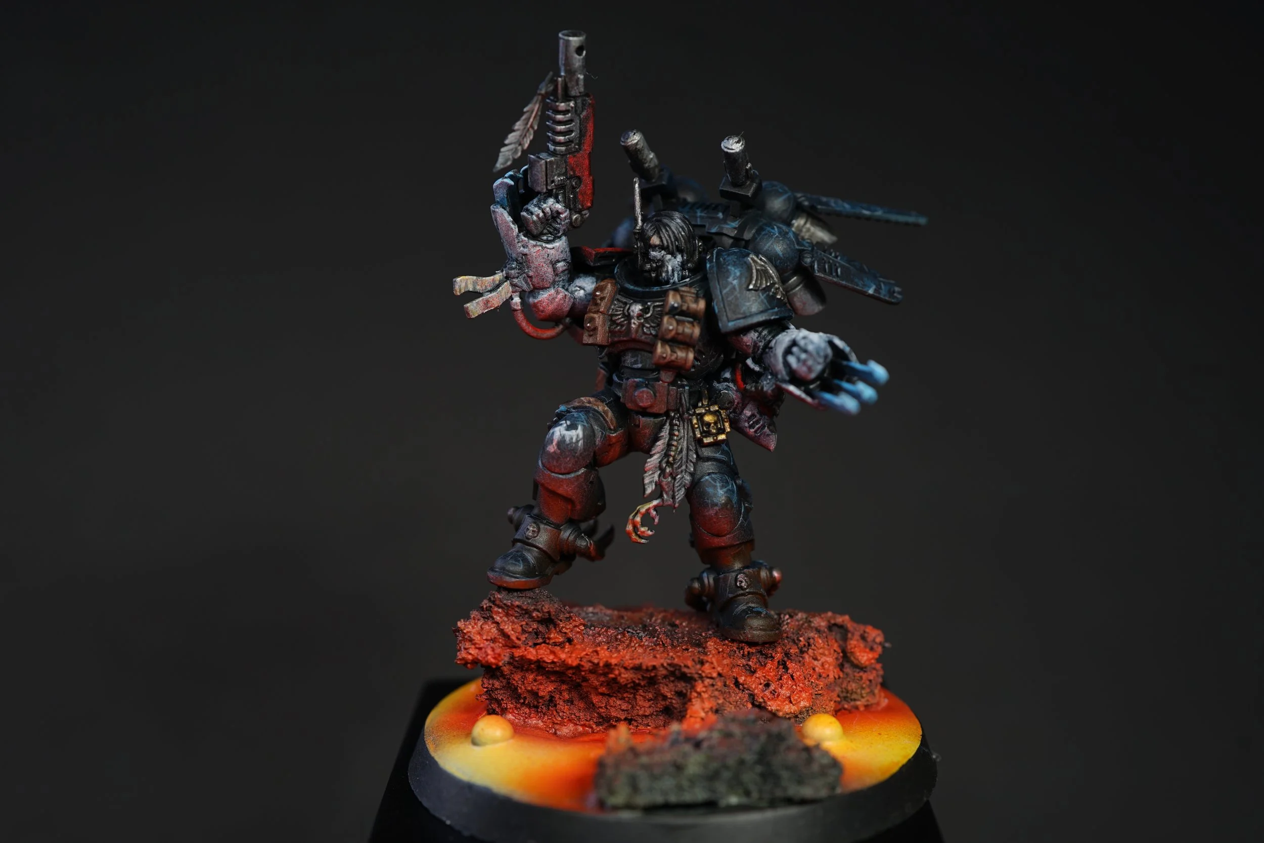 Miniature model of a futuristic armored soldier with weapons, standing on a textured base with a black background.