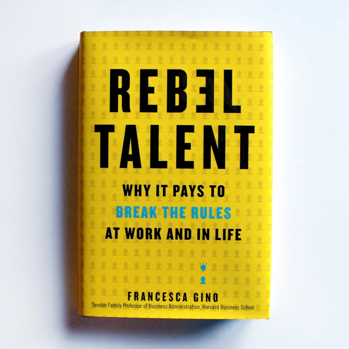 A yellow book titled 'Rebel Talent' with black and blue text, and small icon graphics, resting on a white surface.
