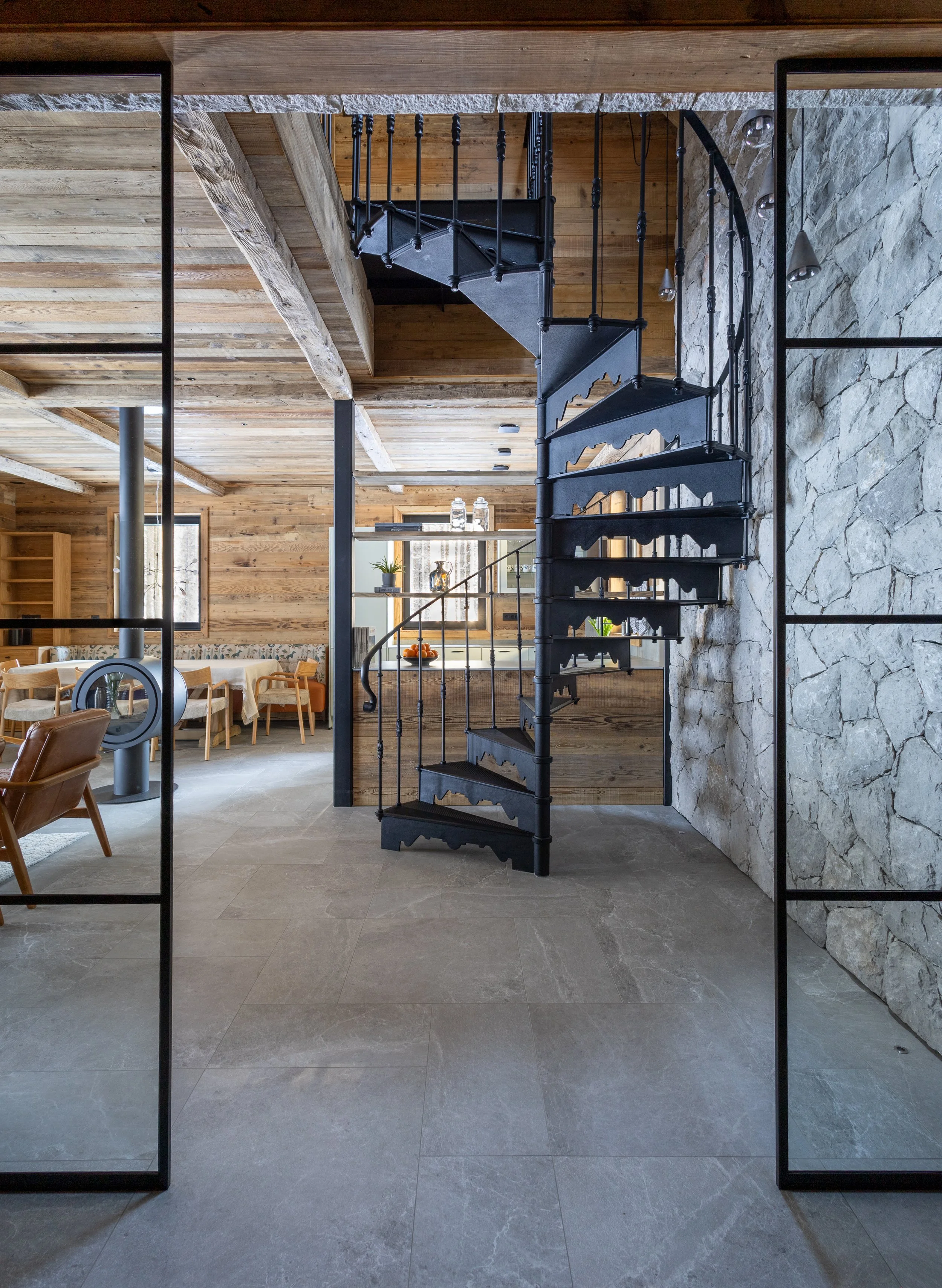 Cast iron spiral staircase and stone wall, mountain chalet living room Julian Alps
