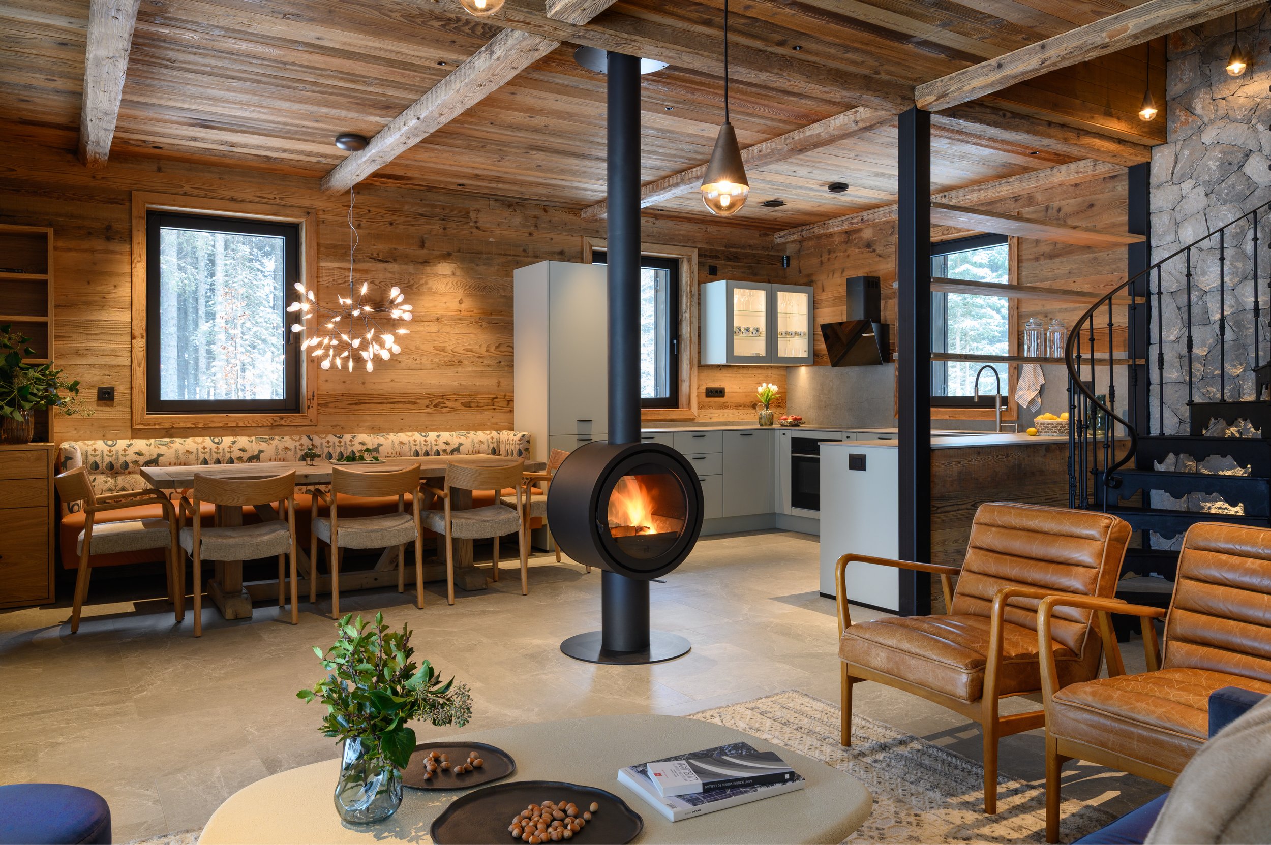 Open plan living dining room kitchen with central fireplace, Julian Alps mountain chalet 