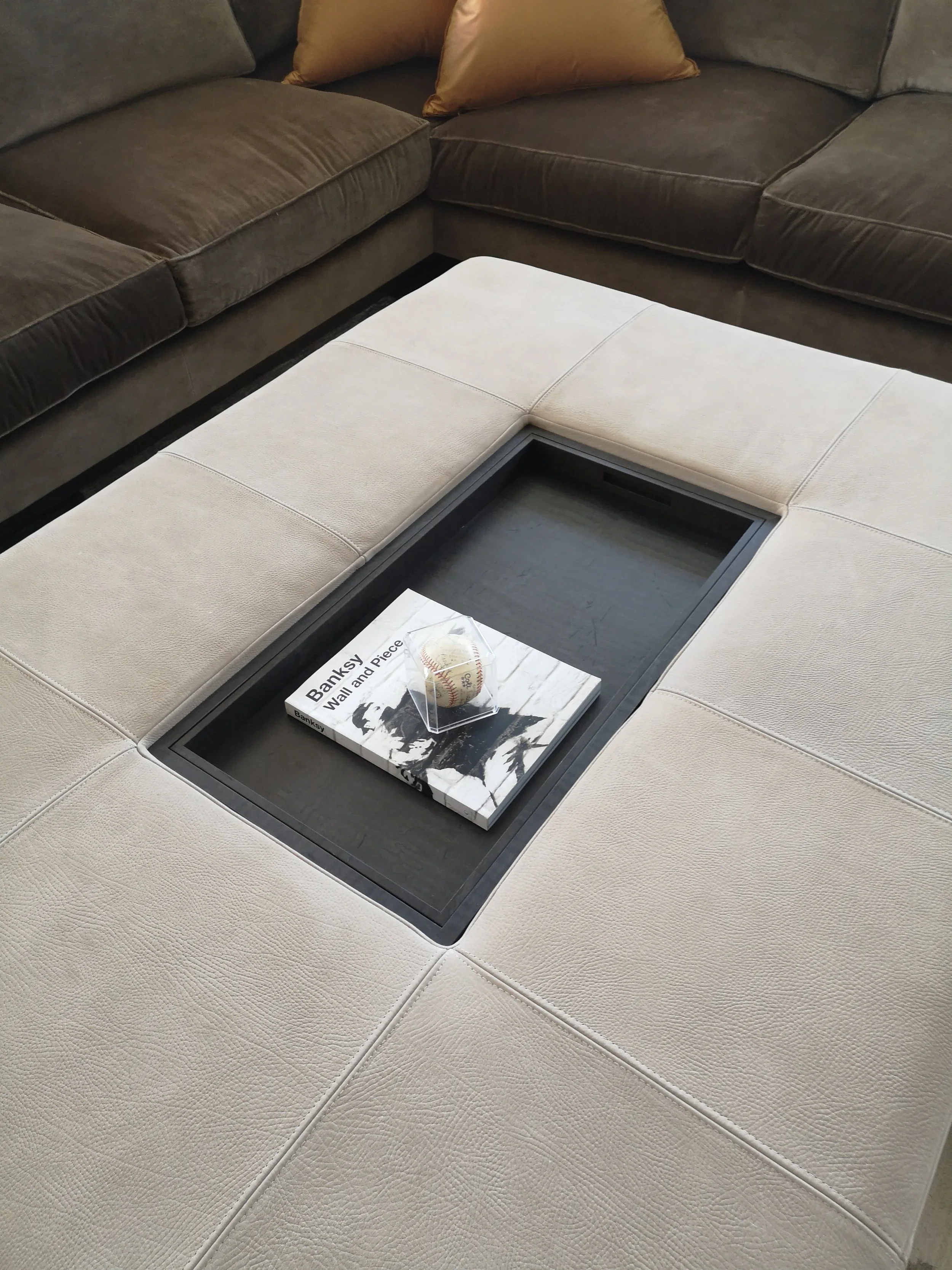 Ottoman coffee table with tray and topstitched leather cushions detail