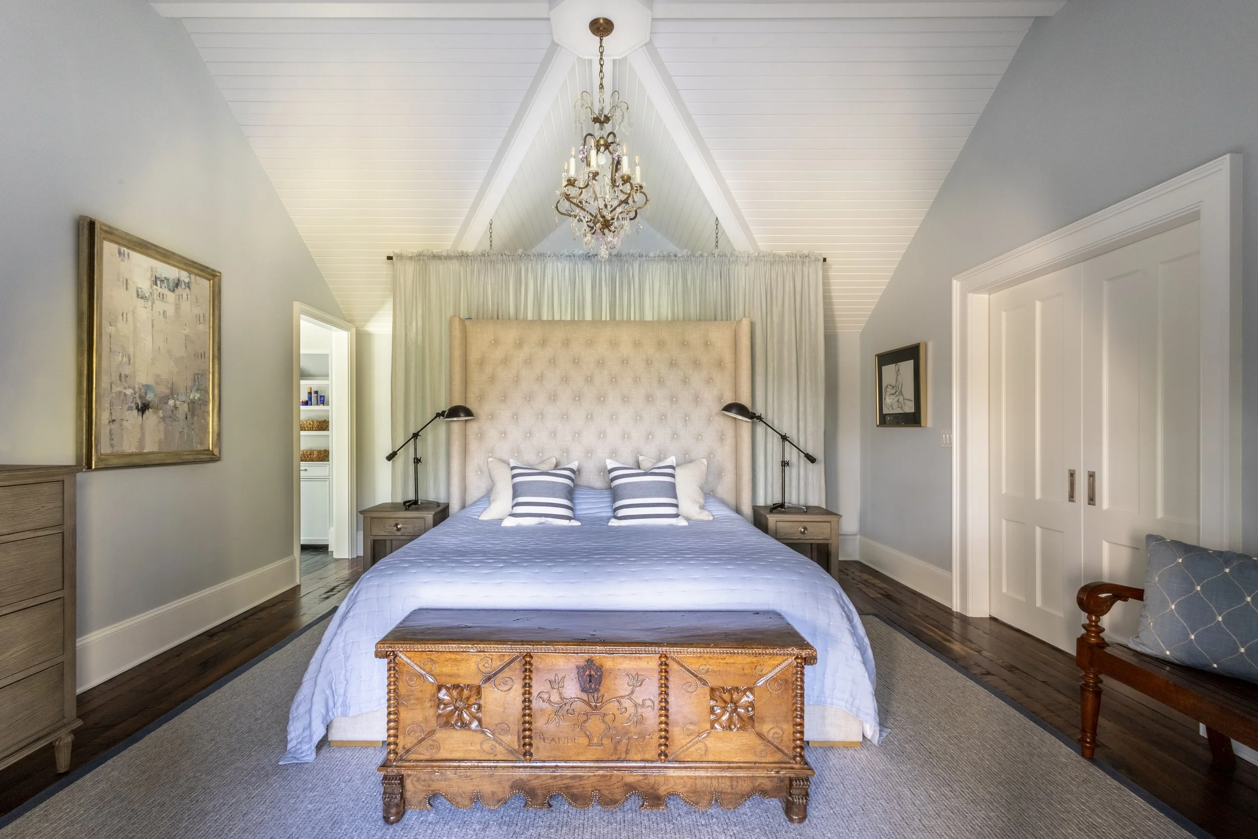 Upholstered bed with tufted headboard and antique blanket chest, bedroom interior, Kiawah Island beach house