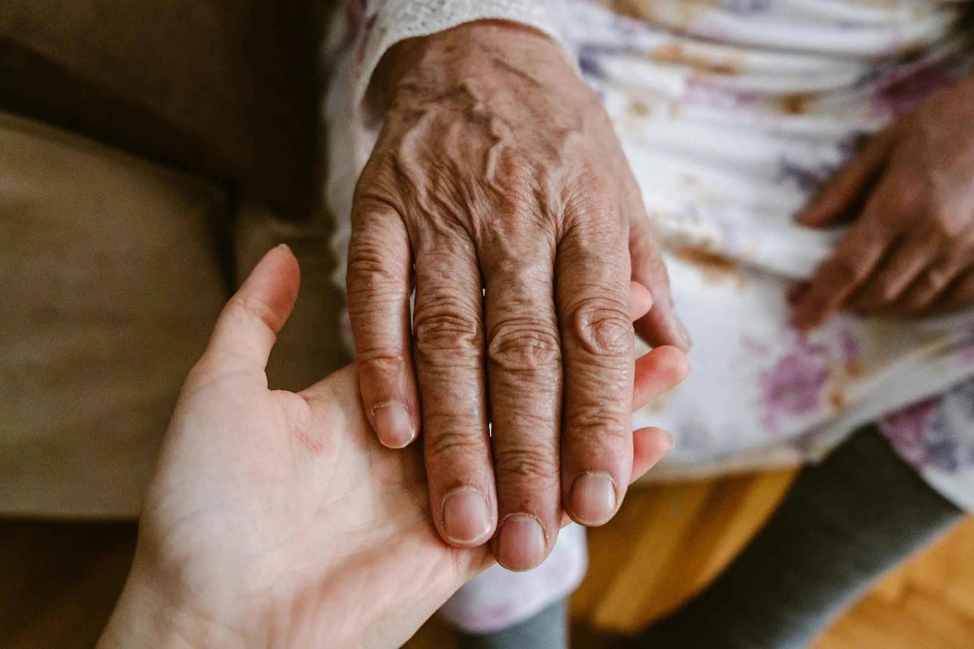 A young person holding an elderly person's hand.