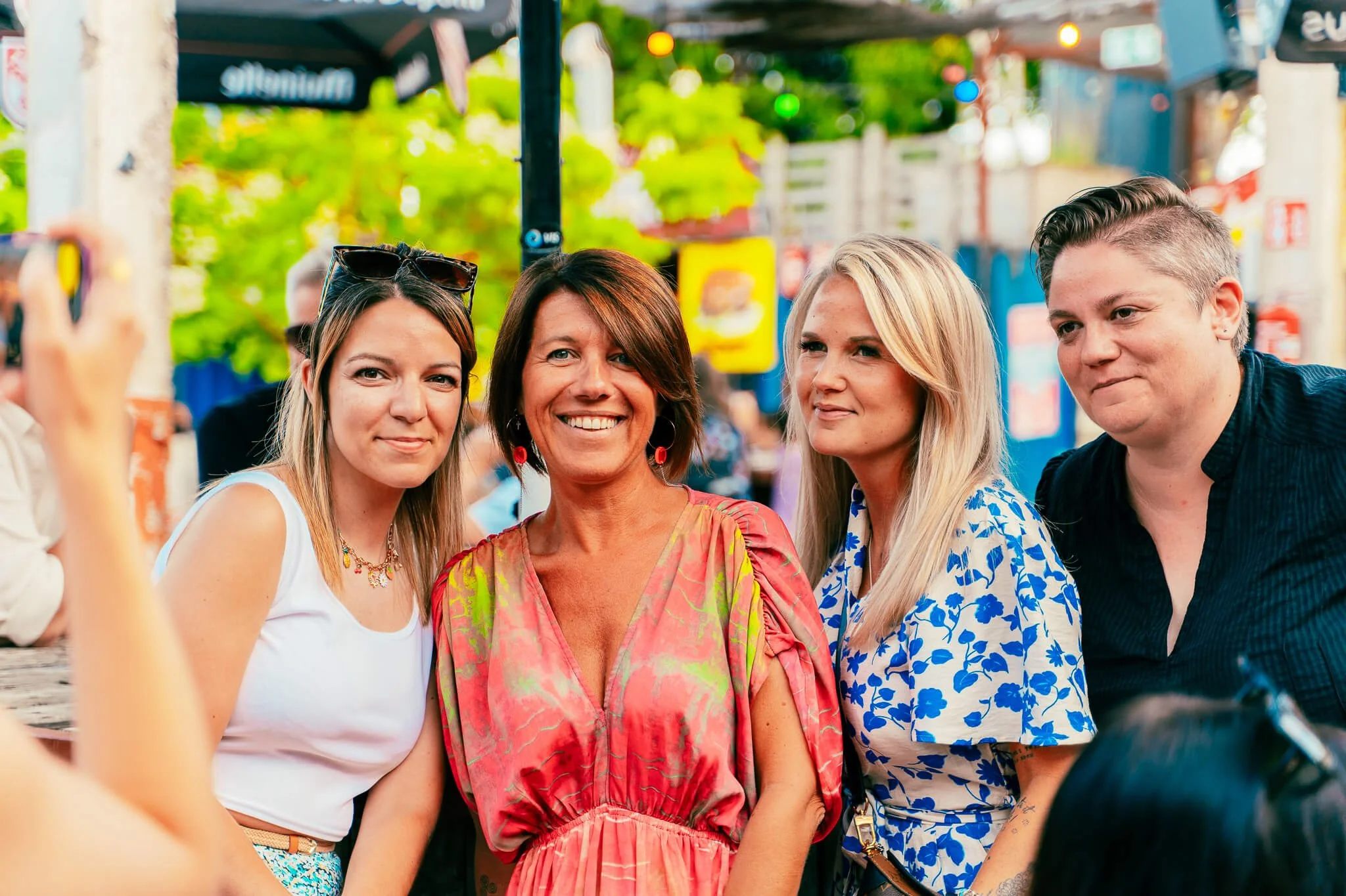 Groupe de quatre femmes posant pour une photo en plein air, dans un cadre coloré et animé