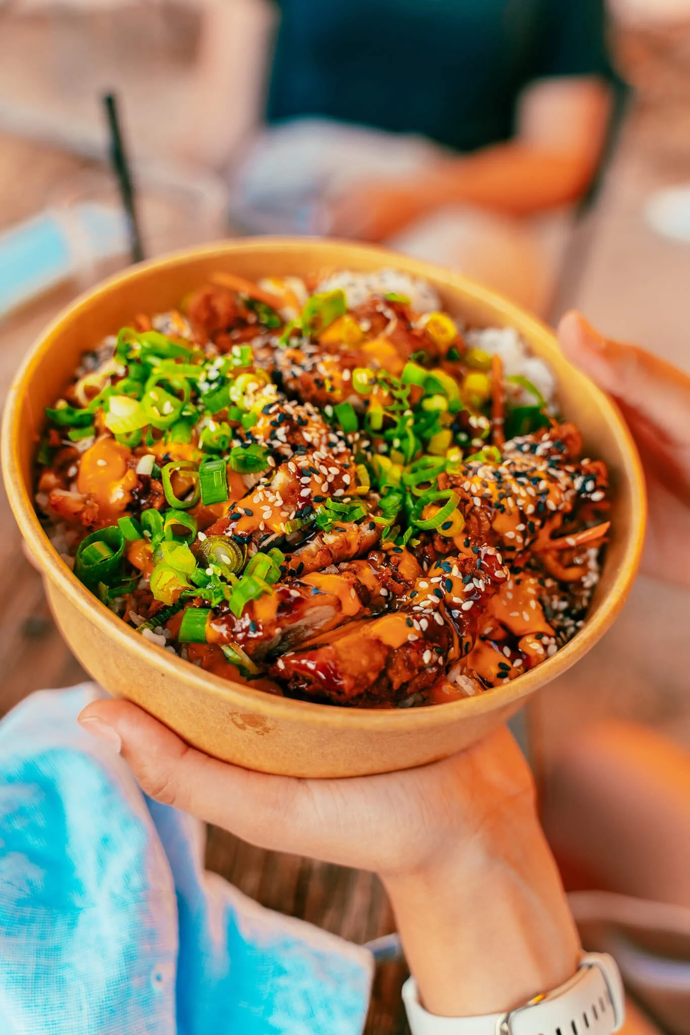 Bol de riz avec du poulet, ses légumes, des oignons verts, des graines de sésame et une sauce soja.