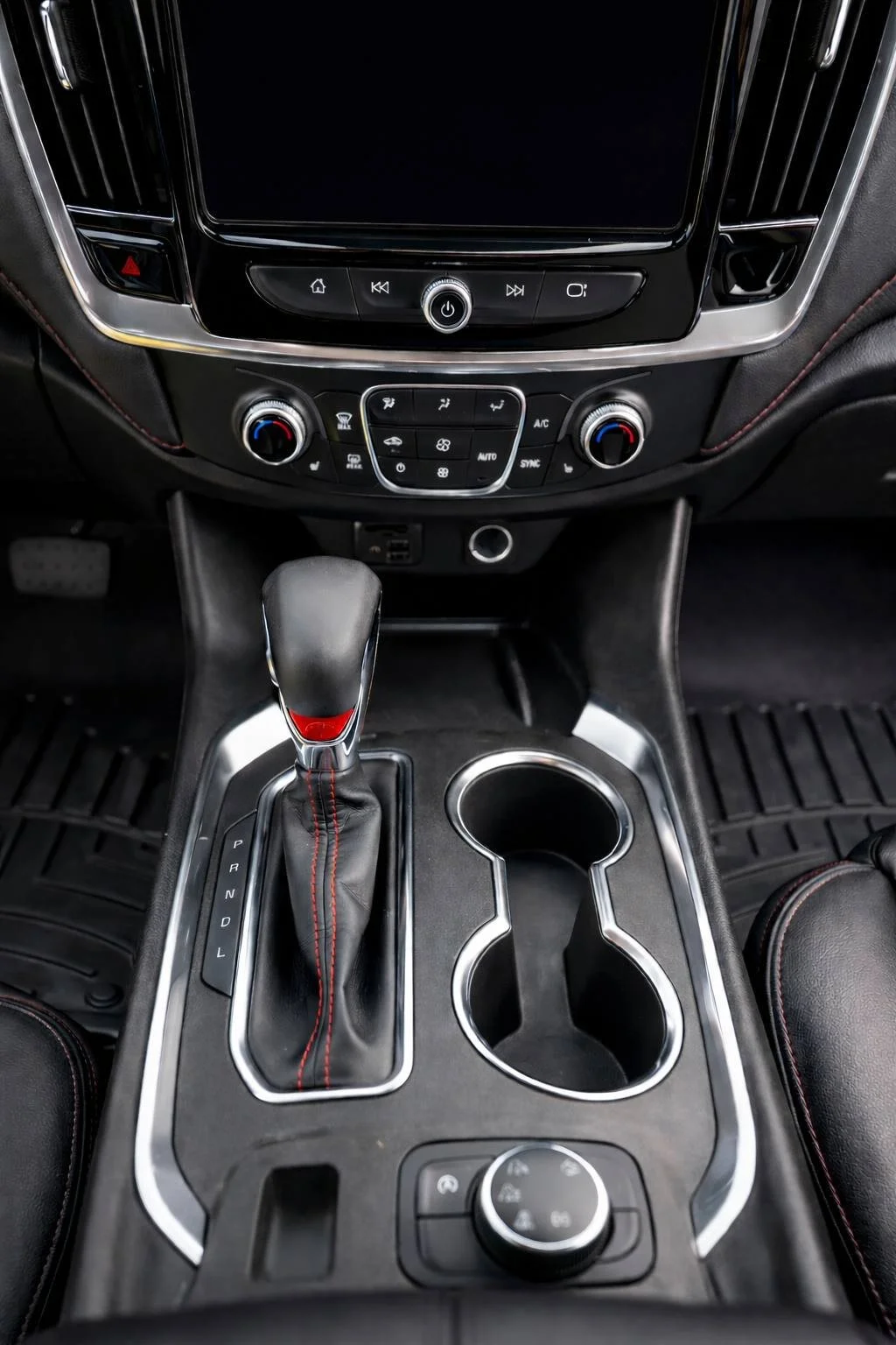 Clean center console of a car with gear shift, cup holders, and dashboard controls.