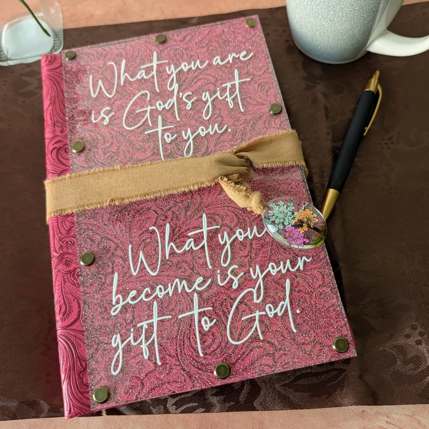 Glitter acrylic with pink embossed leatherette with ribbon and charm wrap closure