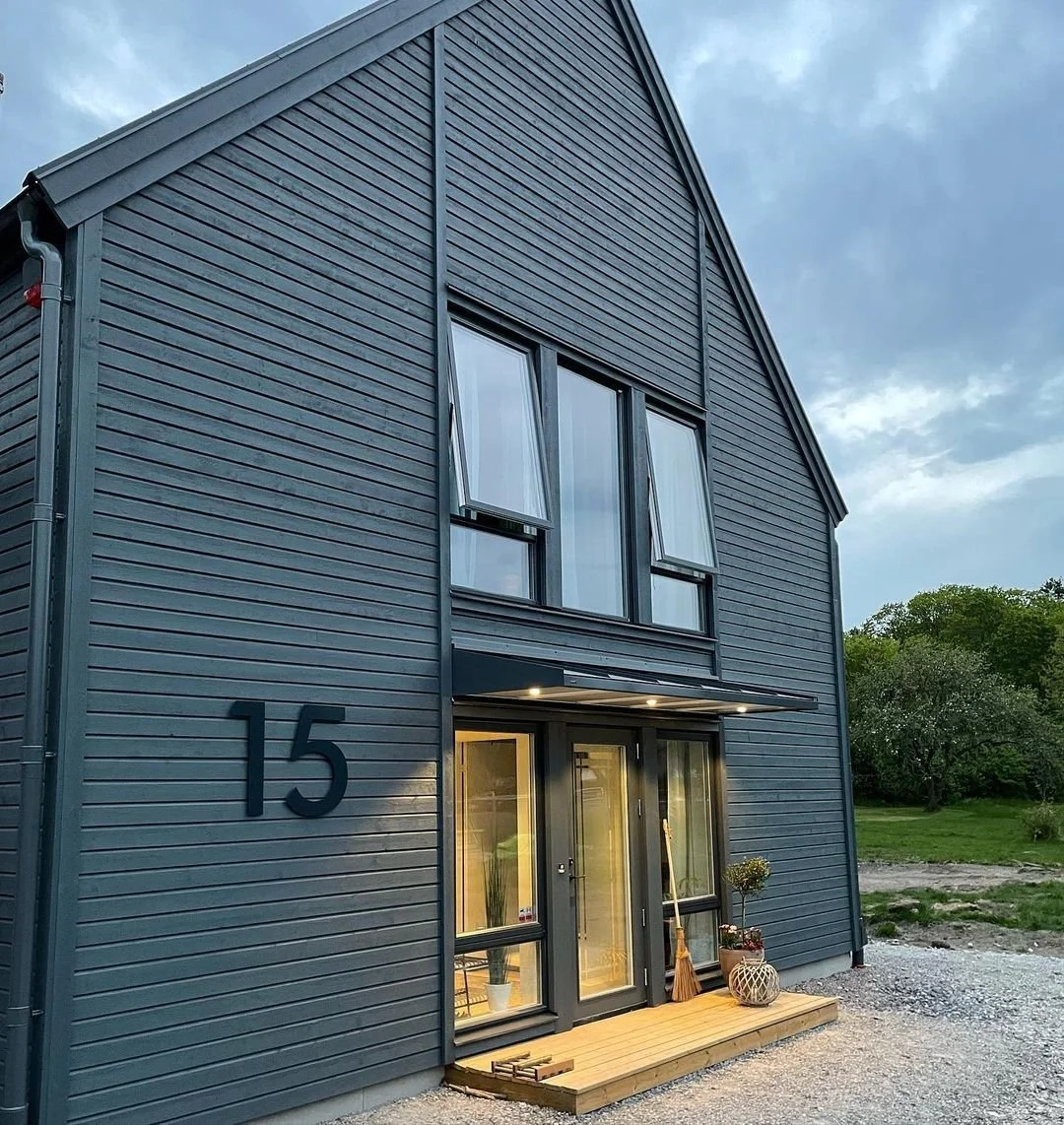Modernt lador-inspirerat hus med husnummer 15 – mörkt grå fasad