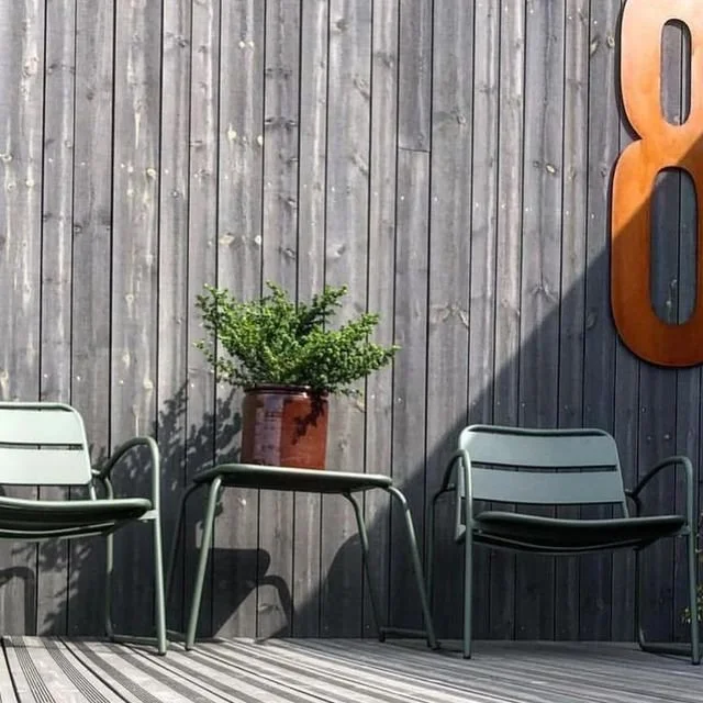 Husnummer 8 i cortenstål på mörk träpanelfasad – rostad patina