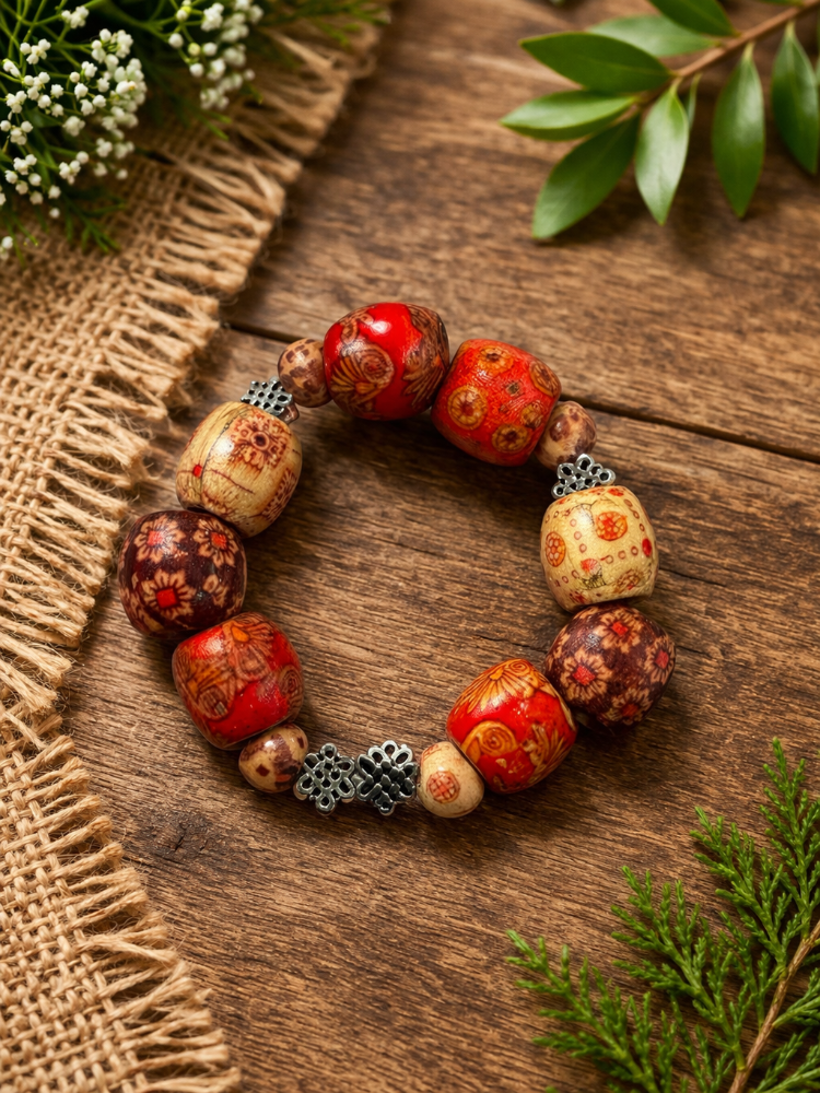 Colorful beaded bracelet with floral and geometric patterns, placed on a wooden surface near green leaves and a burlap fabric.