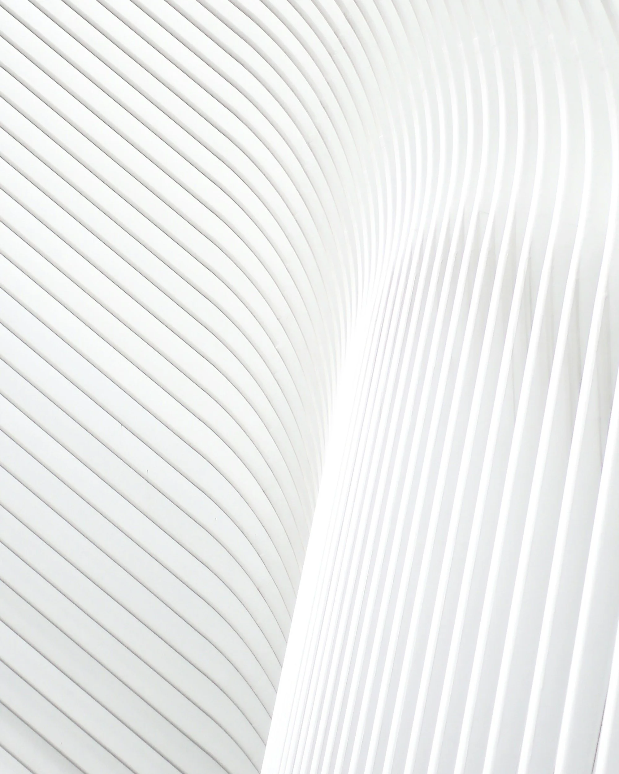 Close-up of a modern architectural structure with white curved, parallel lines creating a sleek, minimalist design.