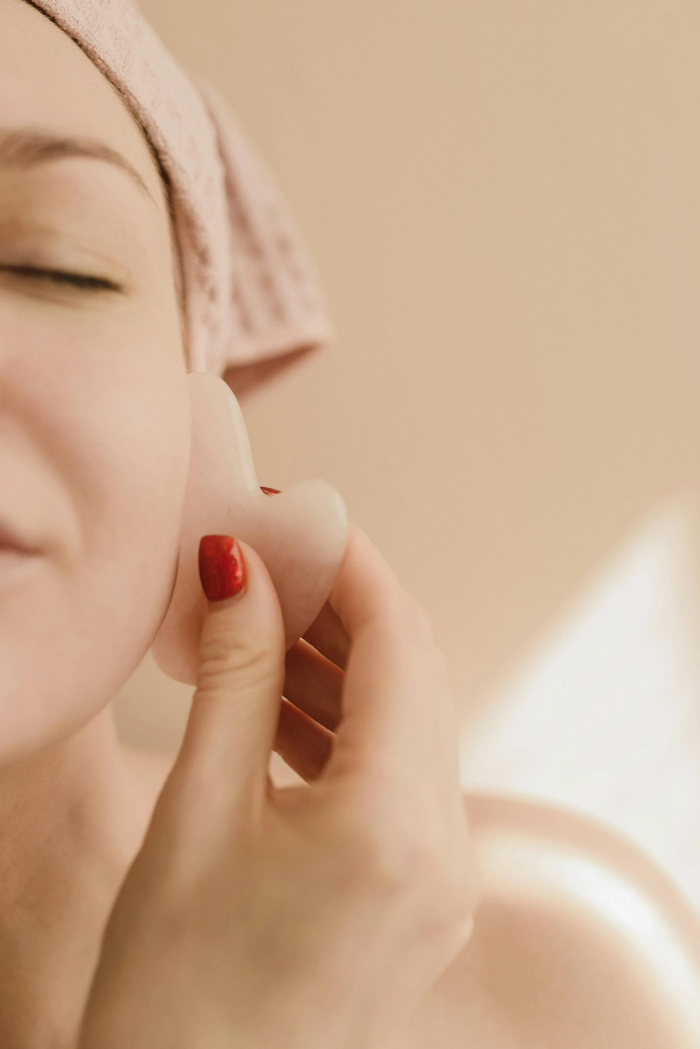 Détail des mains de la facialiste travaillant les tensions du visage et de la nuque.