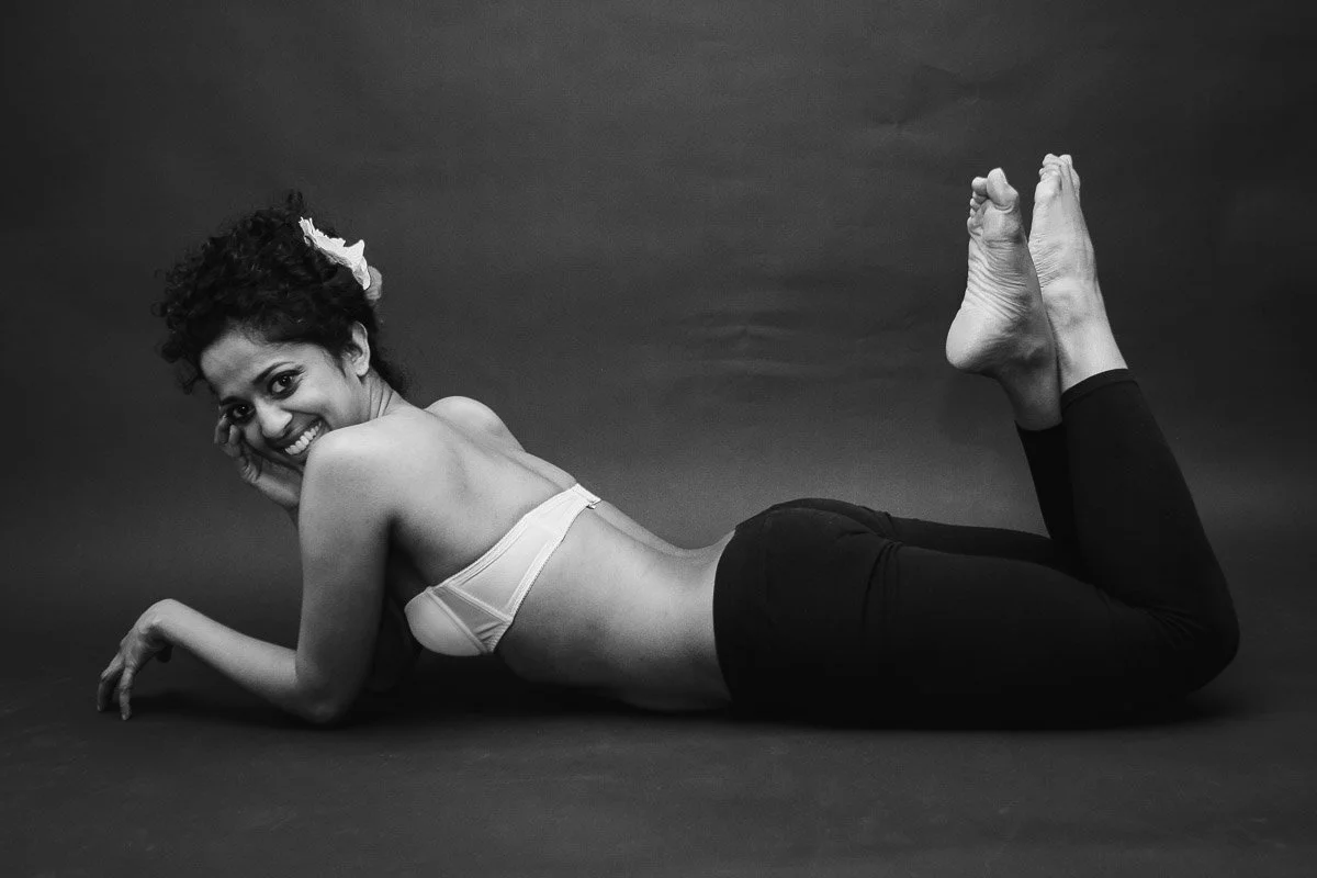 black and white portrait of a girl lying on her tummy while smiling at he camera