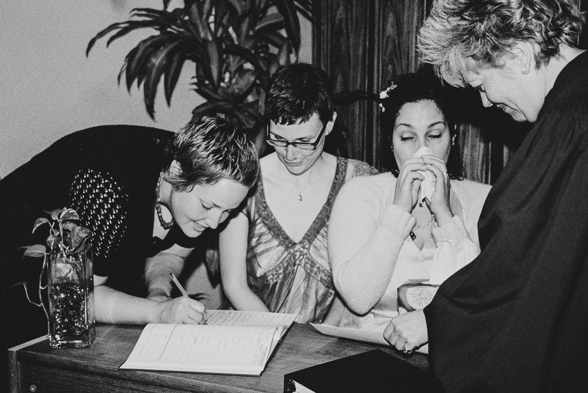 Toronto city hall wedding of same sex couple and one blowing her nose while her sister signs.