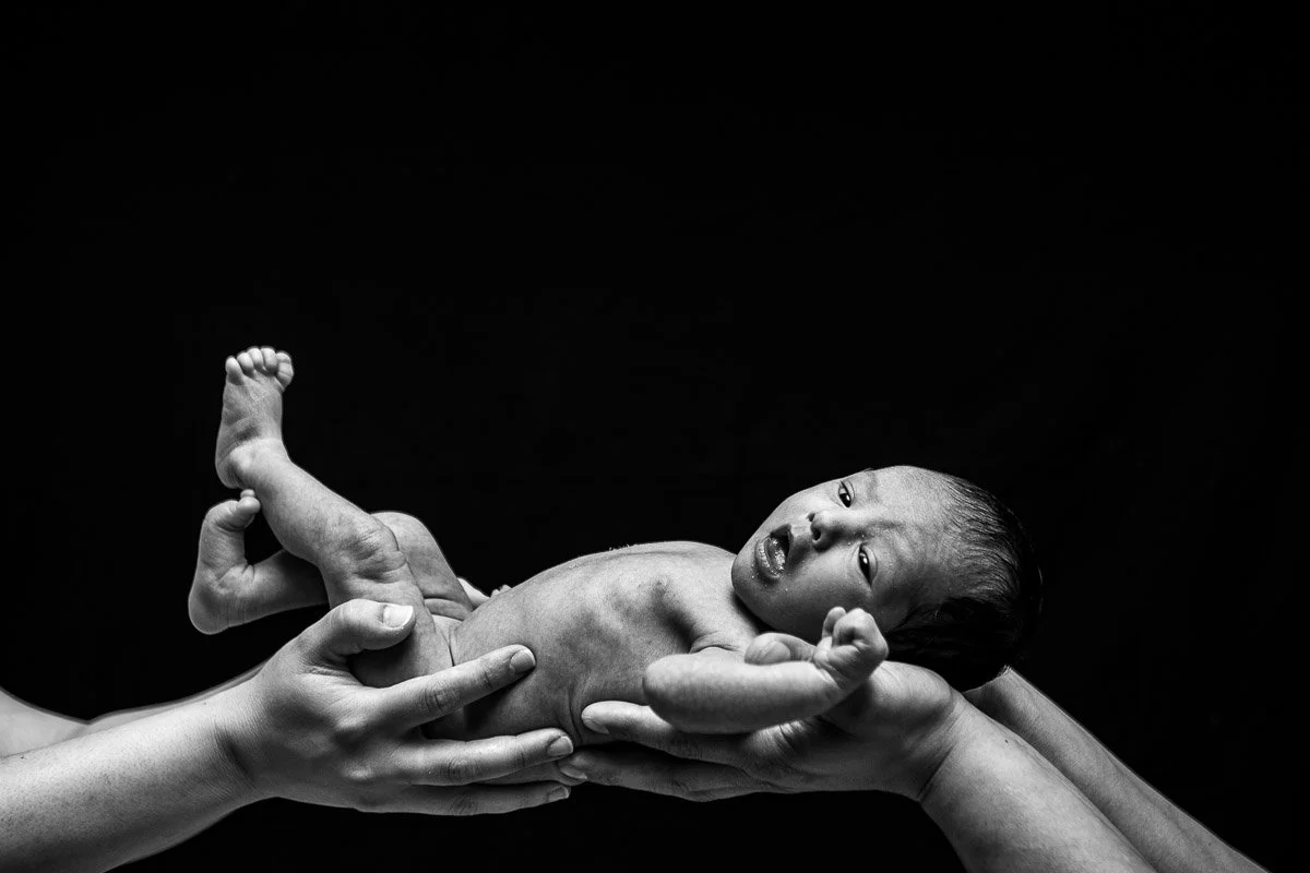 black and white portrait of parents hand holding baby