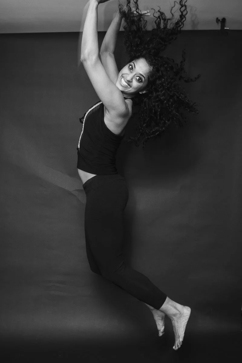 Black and white portrait of girl jumping with joy with the biggest smile