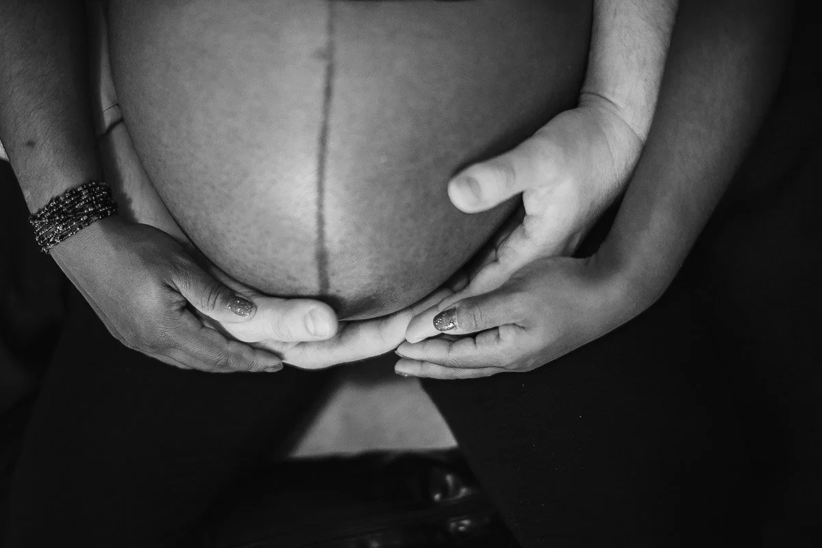 black and white portrait of Interracial couple holding belly