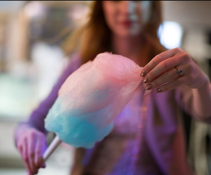 Person holding a large piece of cotton candy with pink and blue colors.