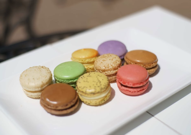 Colorful assorted macarons on a white rectangular plate.